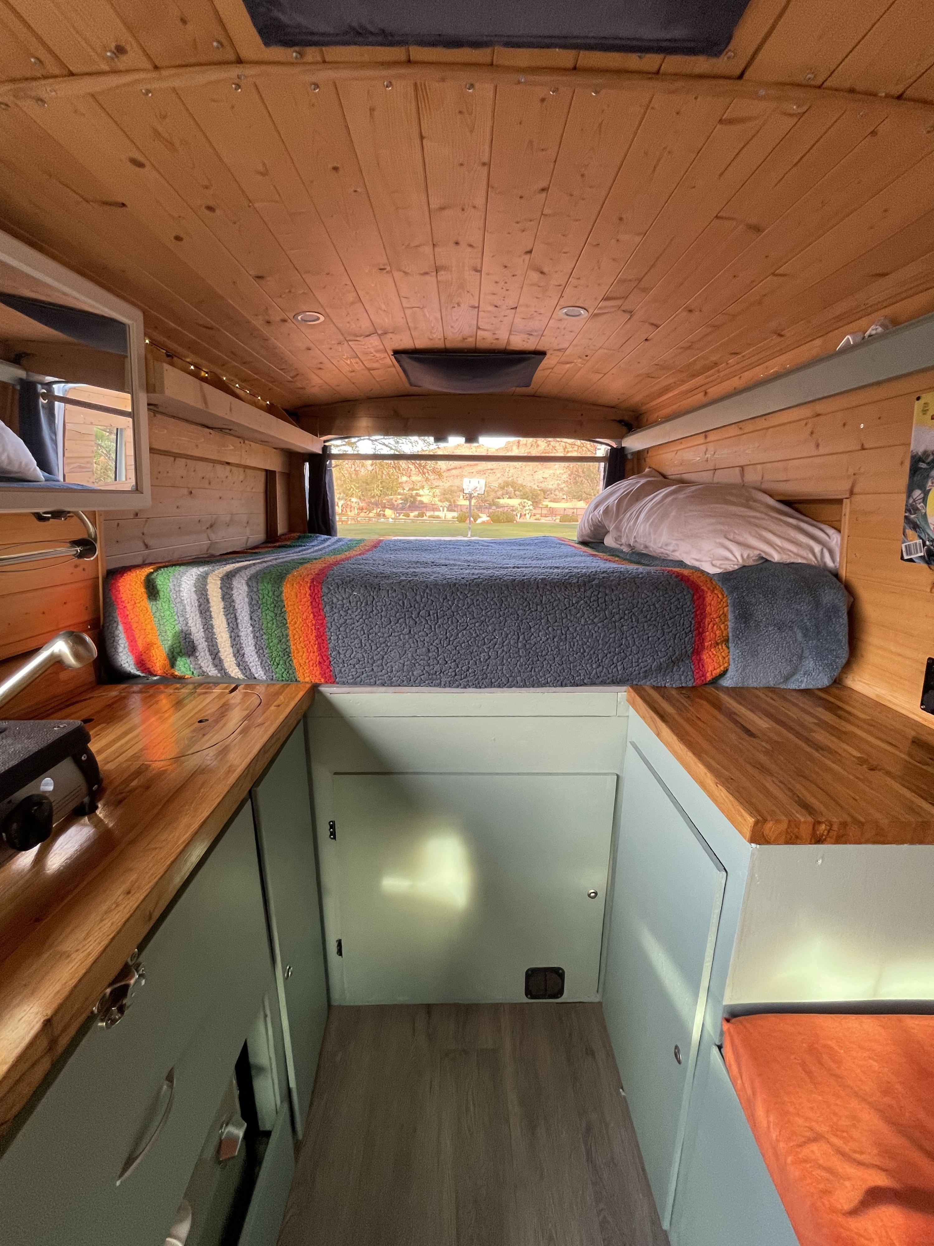 Inside a charming rv rental campervan, featuring a wooden interior, comfortable bed, and a scenic window view.. Ford Transit 2017