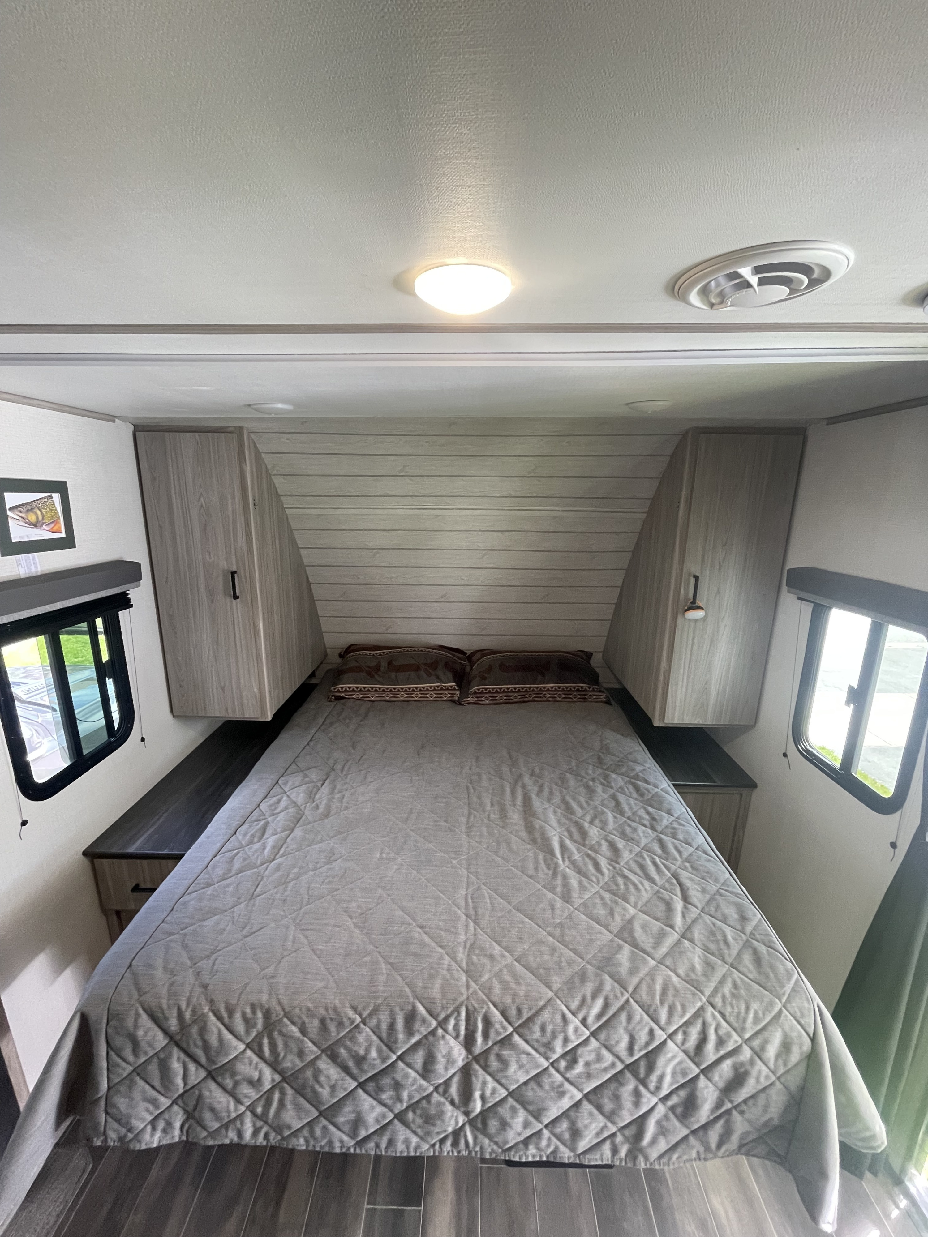 Cozy rv rental bedroom with a large bed, built-in storage cabinets, and bright windows, perfect for travel.. Keystone RV Passport SL 2022