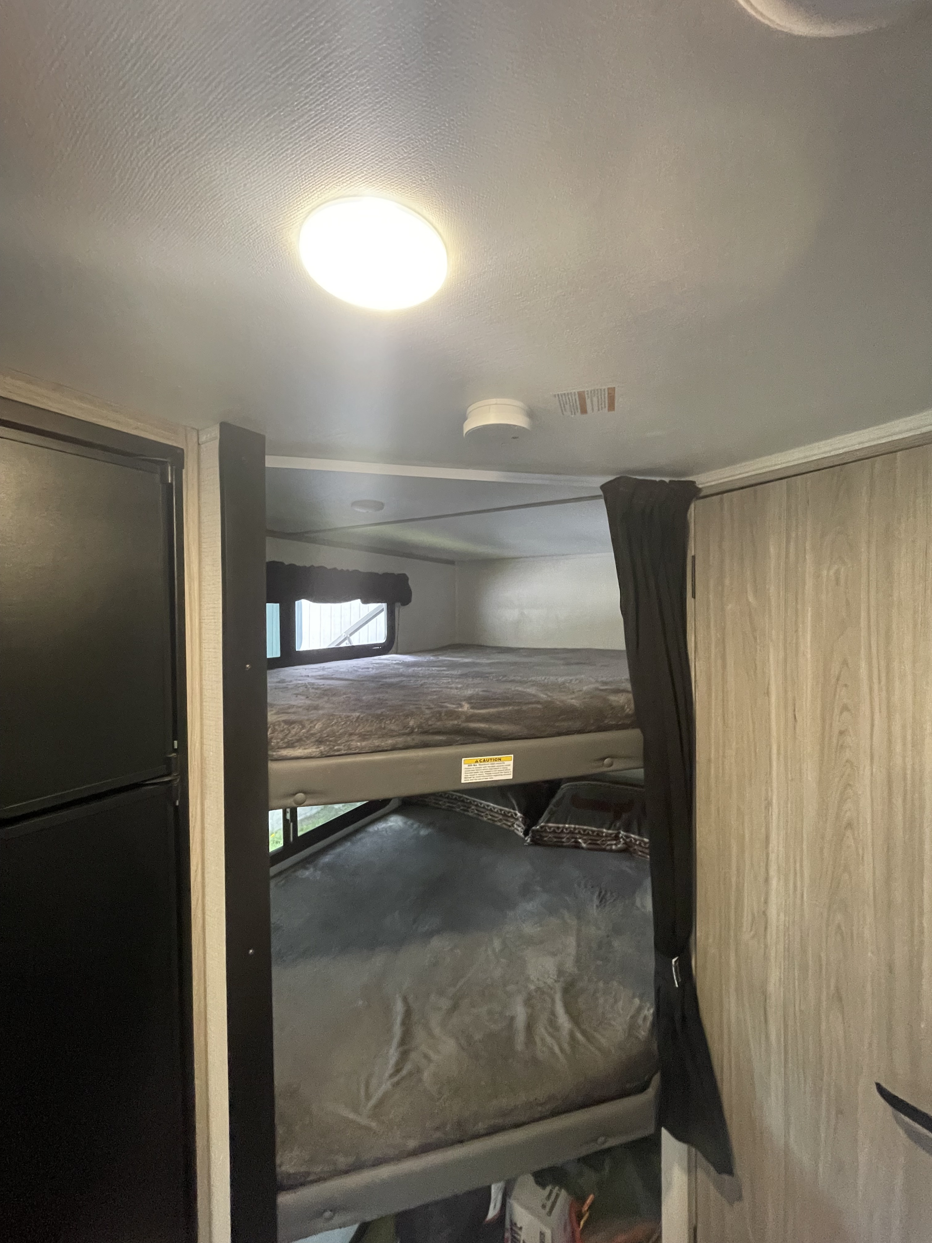 Inside an **rv rental**: A functional bunk bed area with a refrigerator and storage, creating a compact sleeping space for travel.. Keystone RV Passport SL 2022