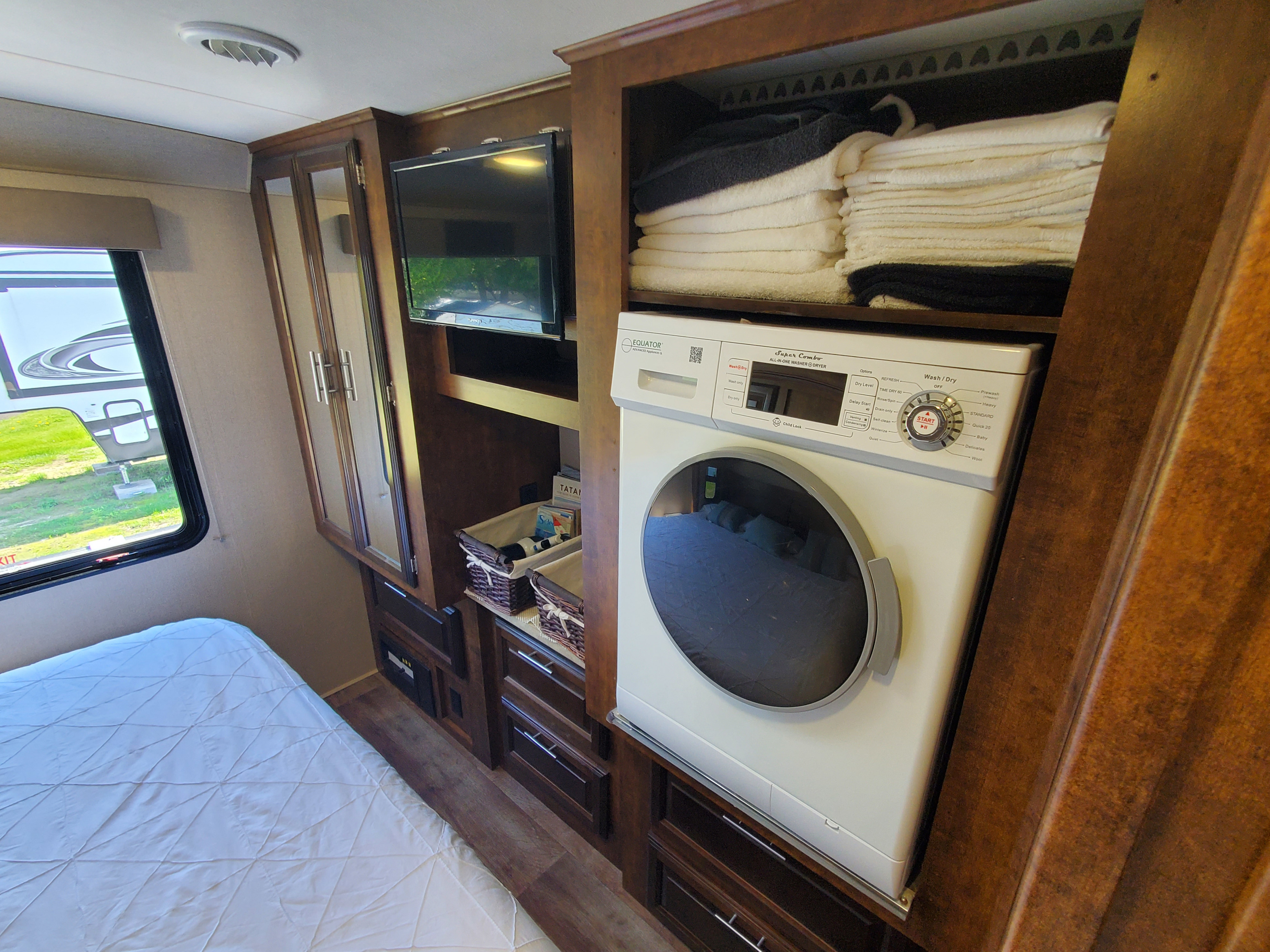 RV rental bedroom with a compact all-in-one washer/dryer, TV, built-in storage, and a window next to the bed.. FR3 FR3 Motorhome 2017
