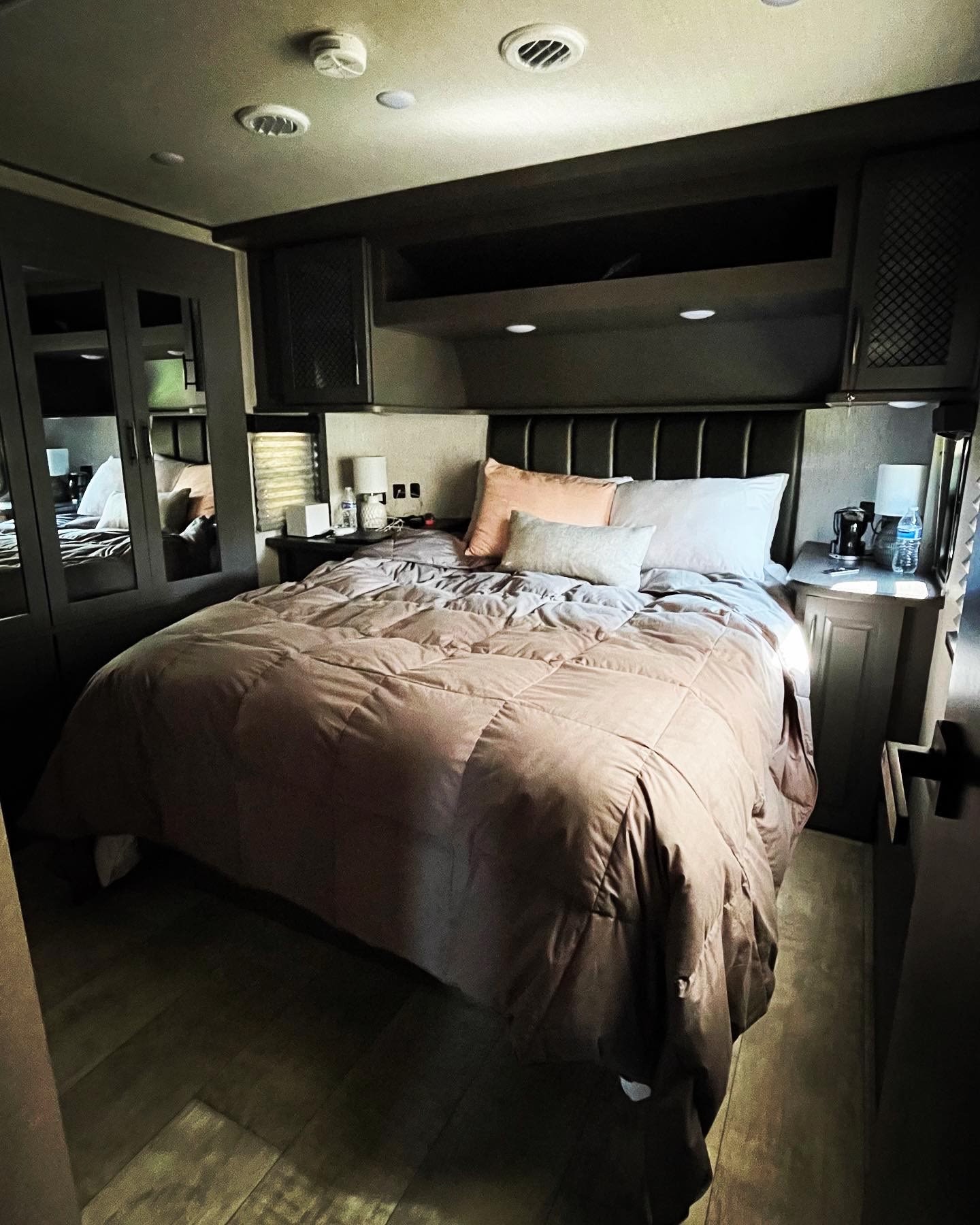 Bedroom view inside an RV rental, featuring a comfortable bed, nightstands, and overhead storage.. Grand Design Momentum 2022