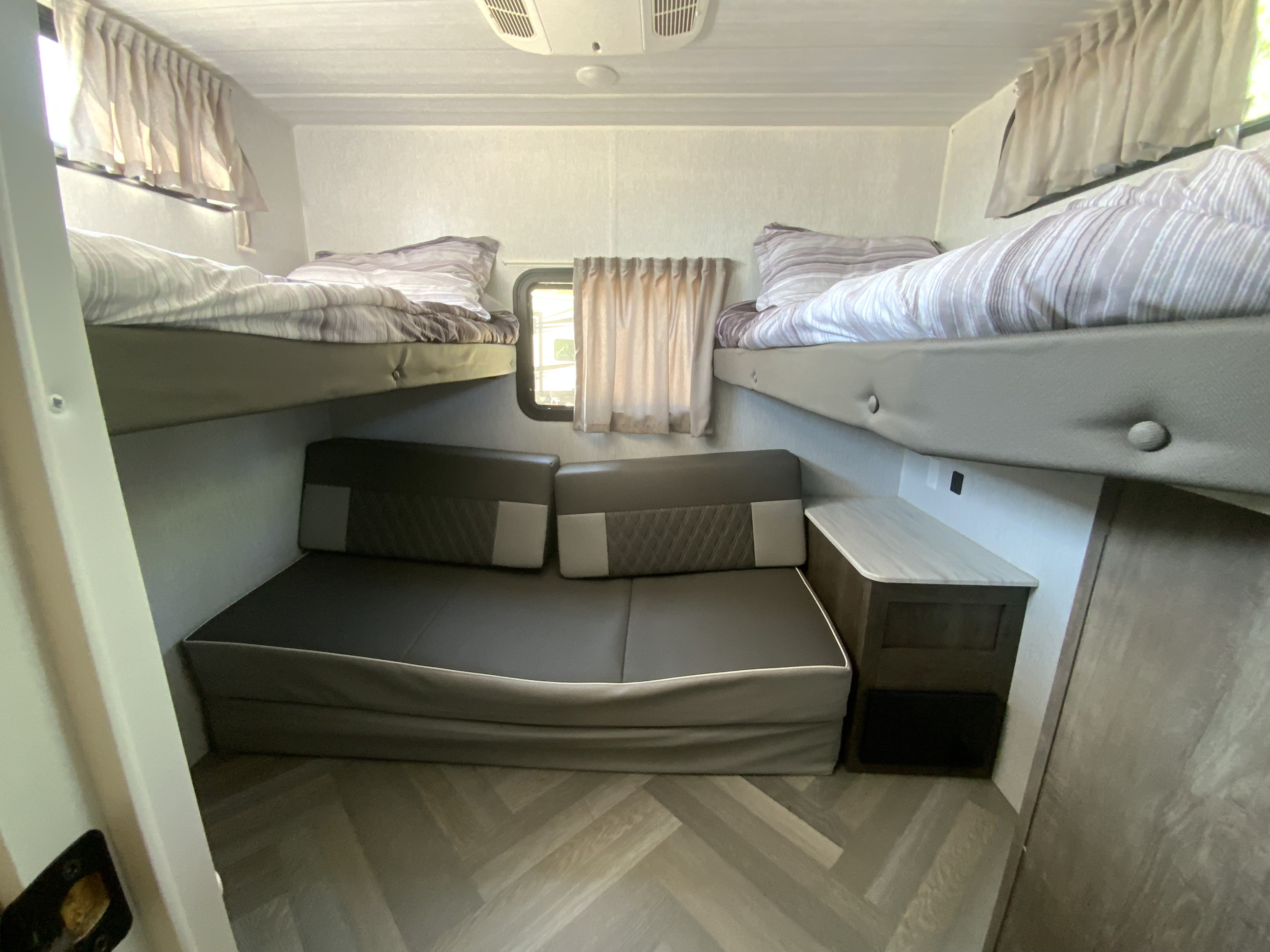 Cozy RV rental interior with bunk beds, a convertible sofa, and a compact counter, providing ample sleeping and lounging space.. Forest River Wildwood X-Lite 2024