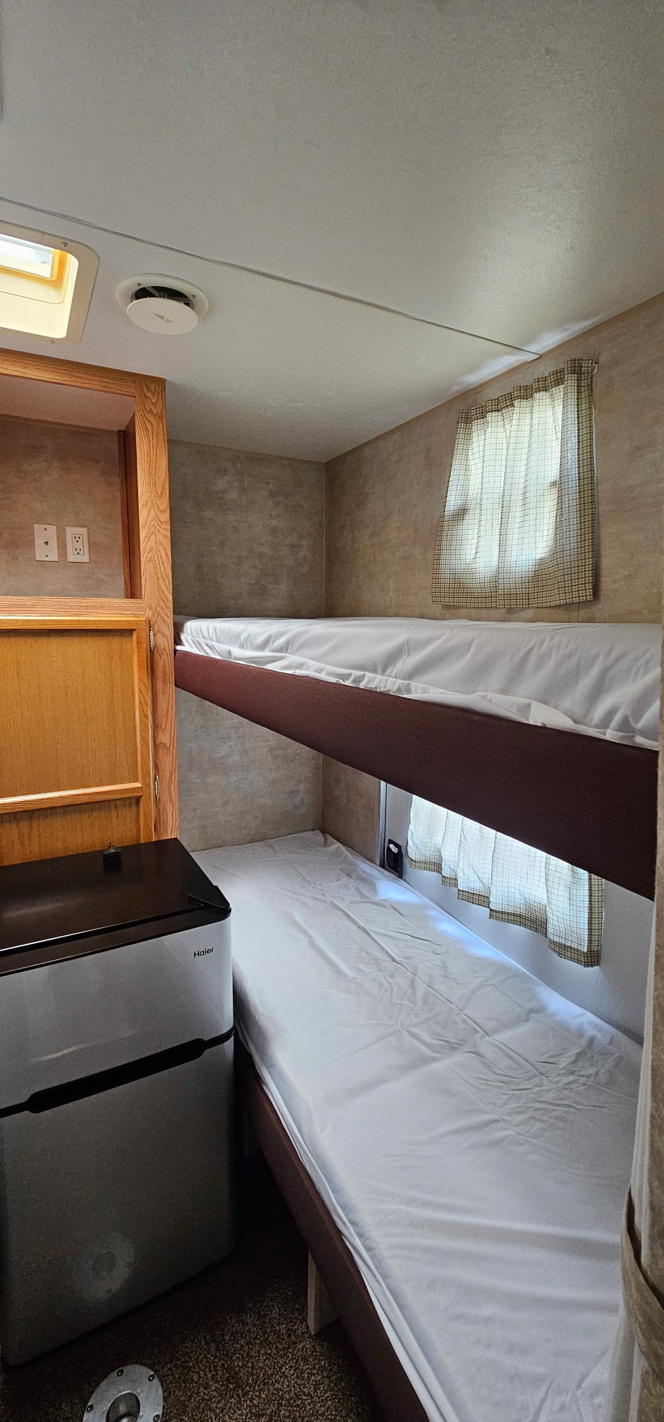Cozy RV rental interior with bunk beds, a mini-fridge, and built-in storage, ideal for compact adventure living.. Jayco Jay Flight 2006