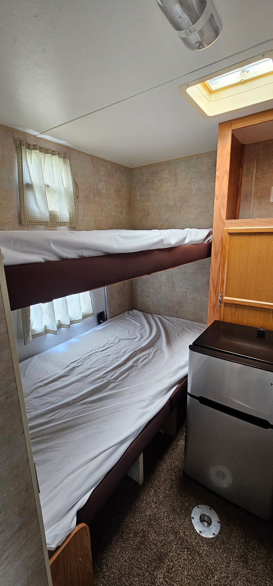 RV rental interior featuring bunk beds with white sheets, a window with curtains, and a compact refrigerator.. Jayco Jay Flight 2006