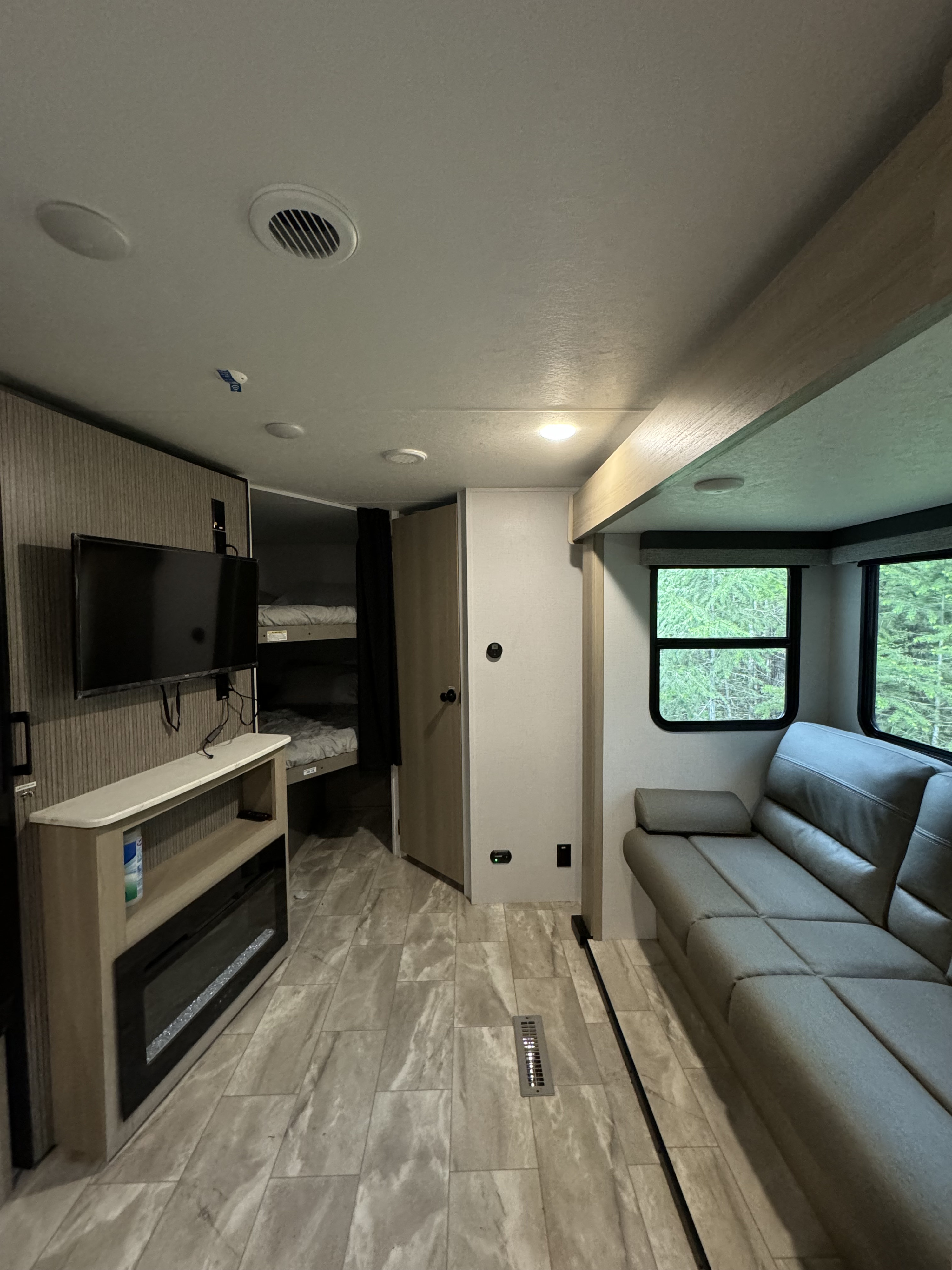This spacious RV rental features a modern living area with a comfy sofa, TV, electric fireplace, and separate bunk beds.. Dutchmen Kodiak 2025