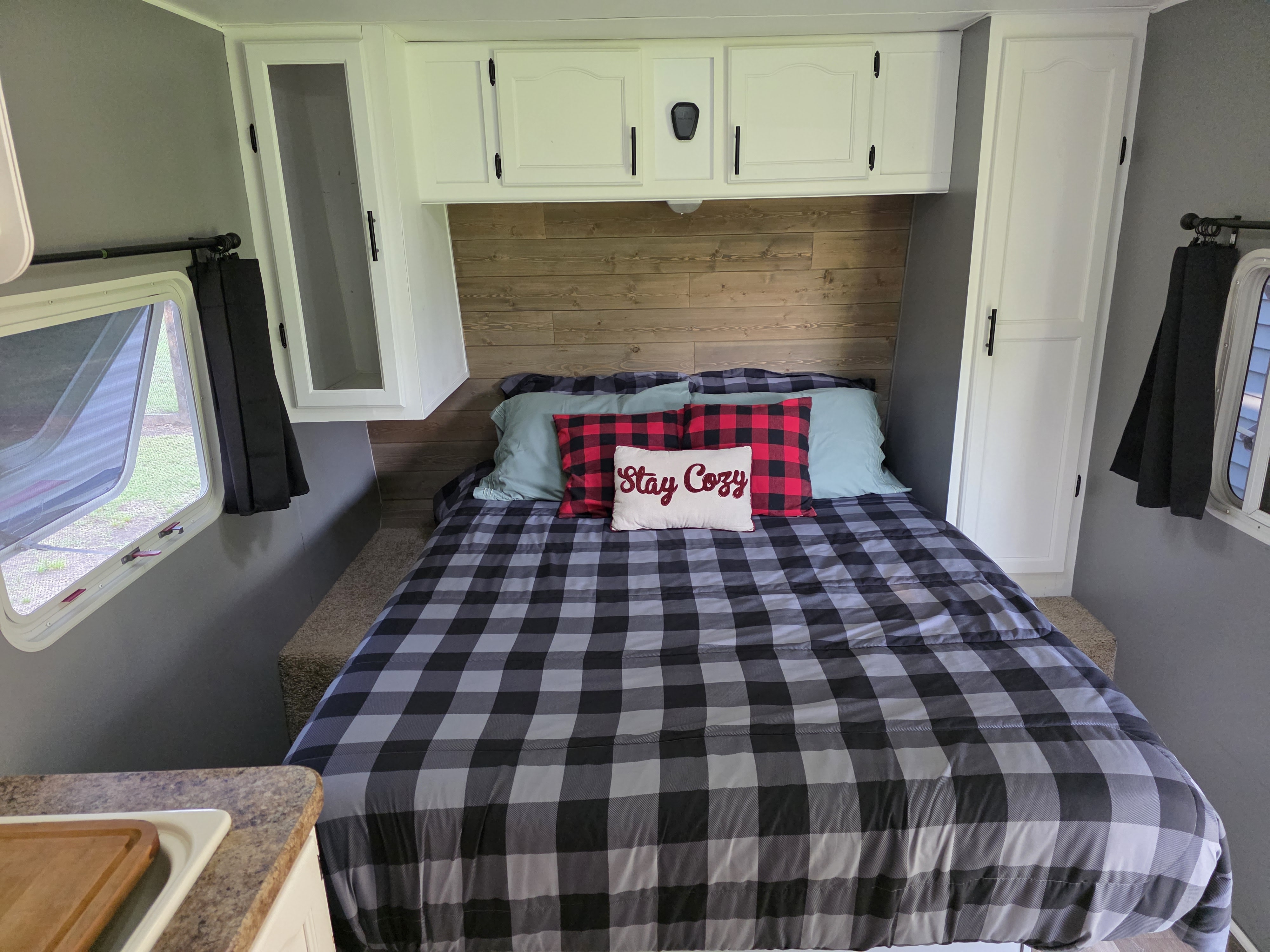 Step into this cozy RV rental bedroom featuring plaid bedding, a wood accent wall, and ample storage for a comfortable getaway.. Gulf Stream Innsbruck-Lite 2008