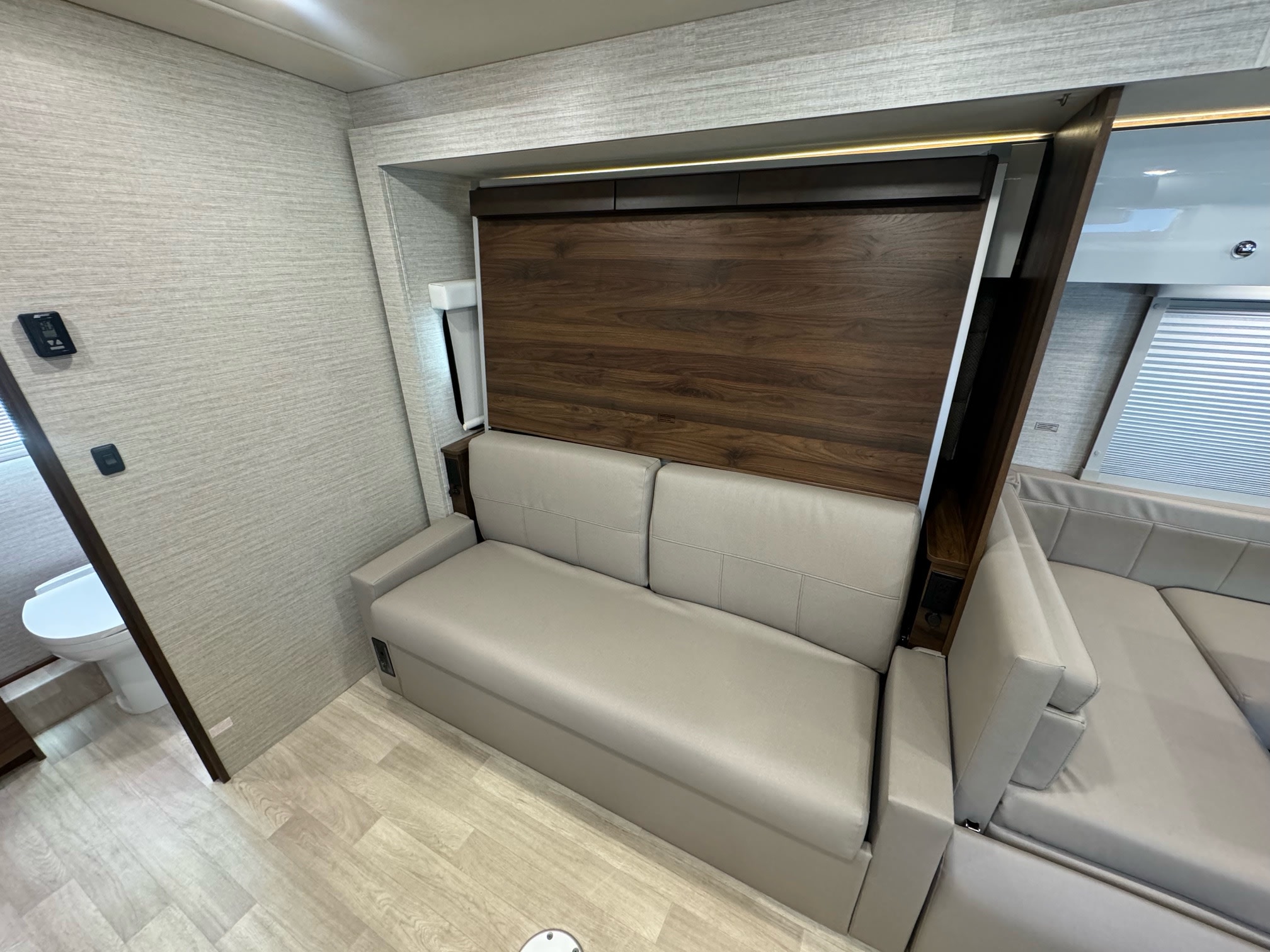 RV rental interior: A light gray convertible sofa optimizes this modern, compact living space with sleek wood details.. Winnebago View 2024