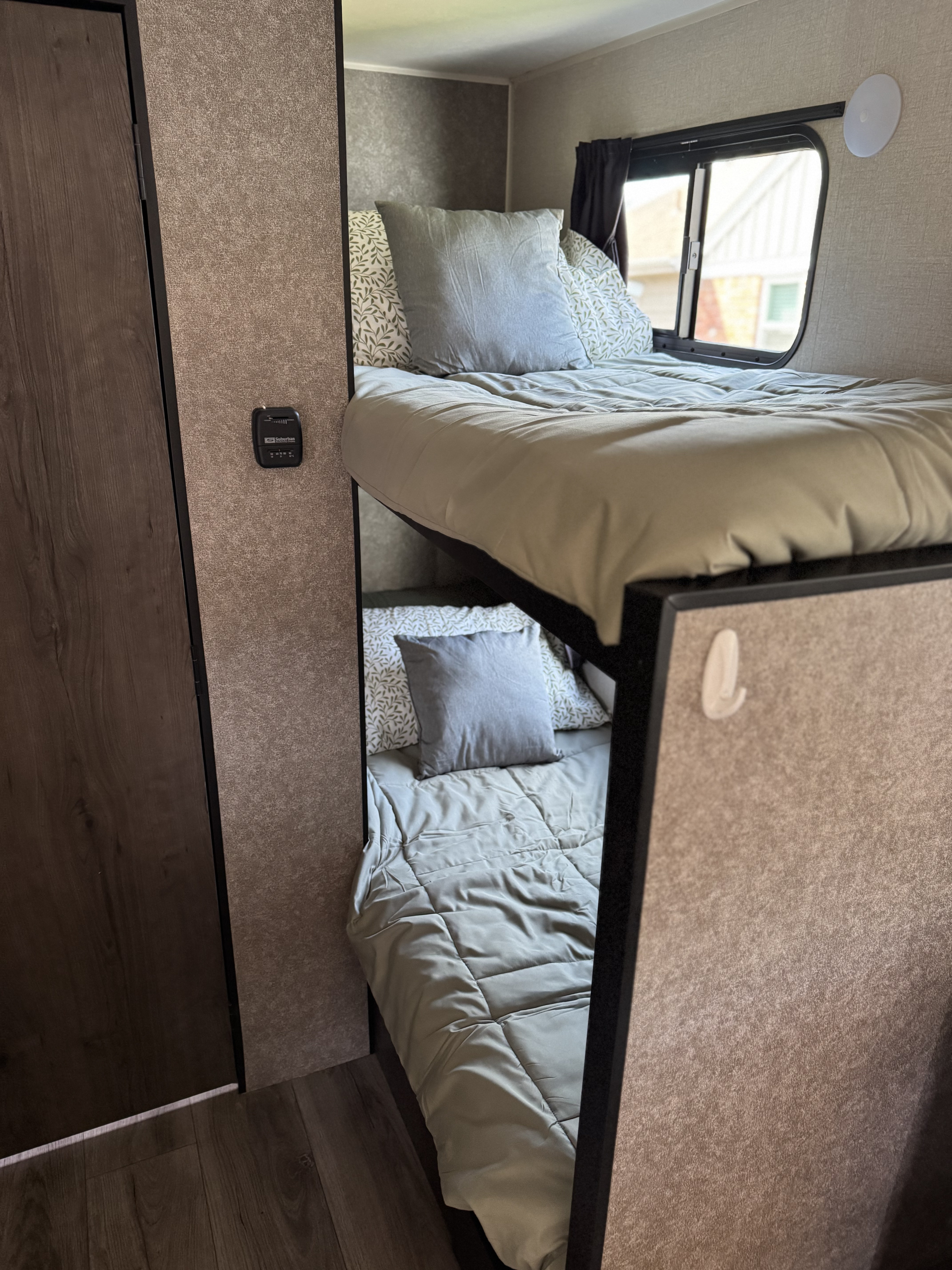 Cozy RV rental interior with stacked bunk beds, light bedding, a window, and an RV thermostat. Ready for travel!. Starcraft Autumn Ridge 2021