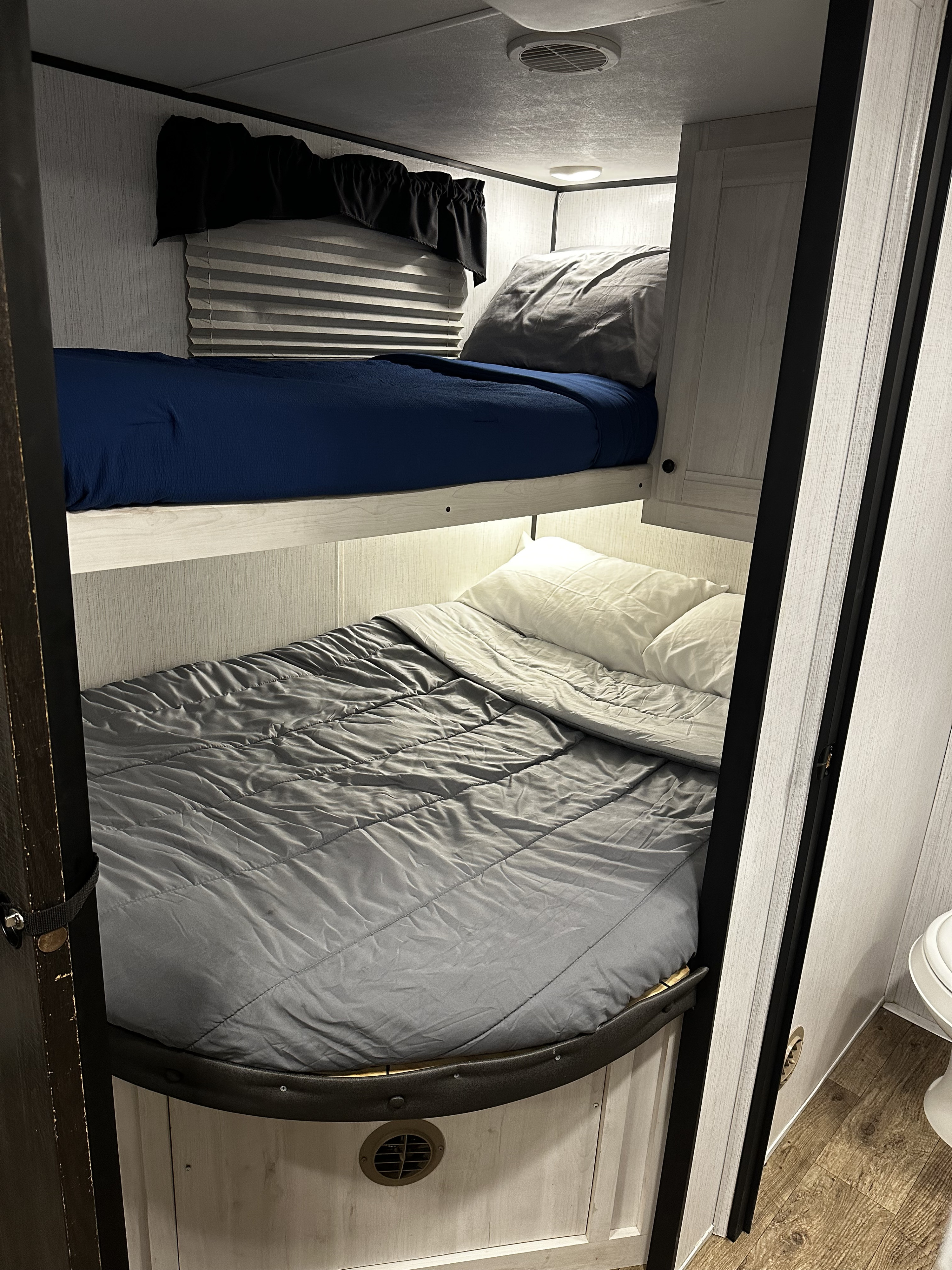 Cozy RV rental bunk beds with clean blue and grey bedding, offering comfortable travel accommodations.. 5sfeb3729me459252 31DB 2021
