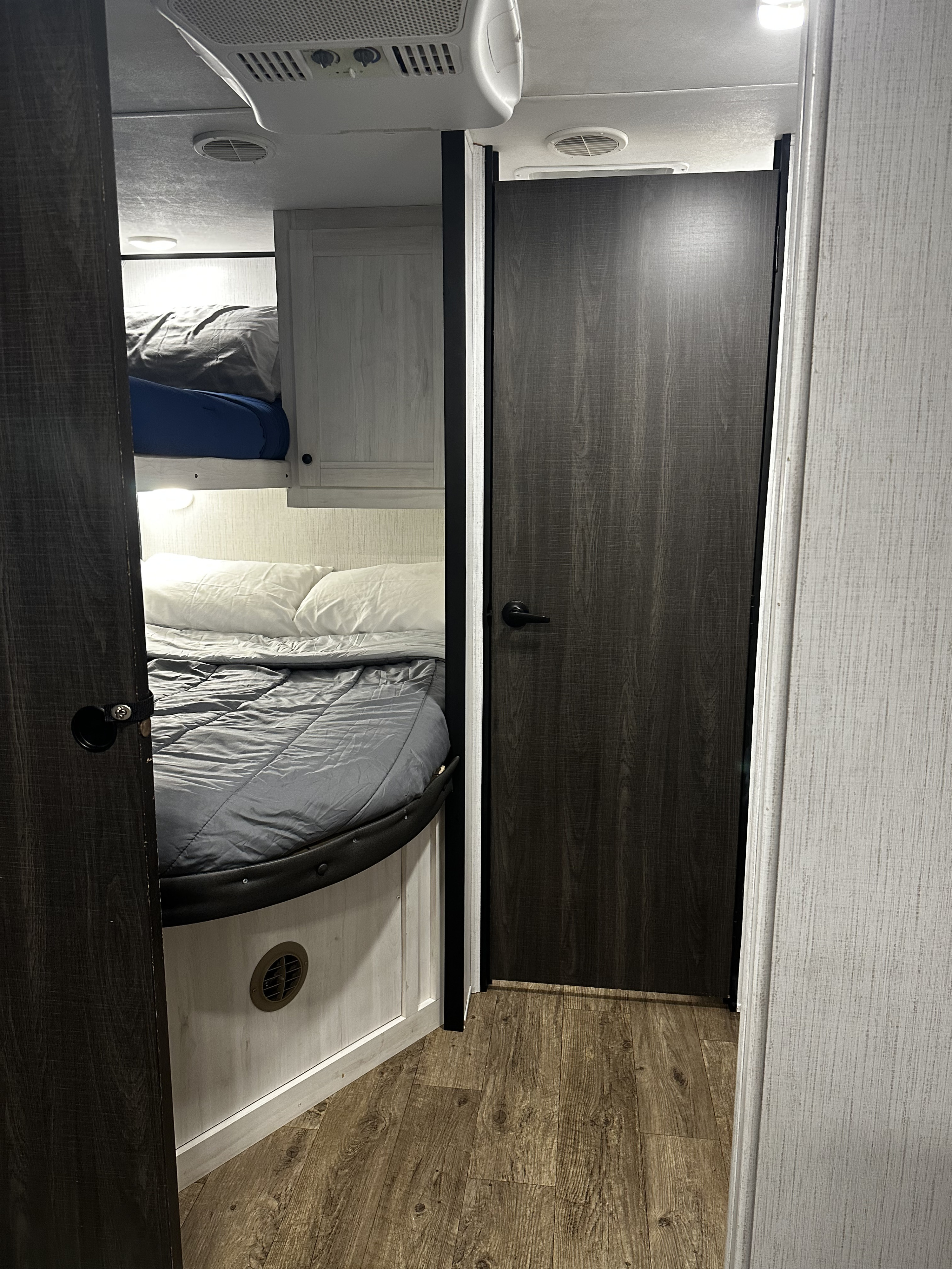 RV rental bunk bed sleeping area. Features two bunks, ceiling AC, and a dark wood door, showcasing compact mobile living.. 5sfeb3729me459252 31DB 2021