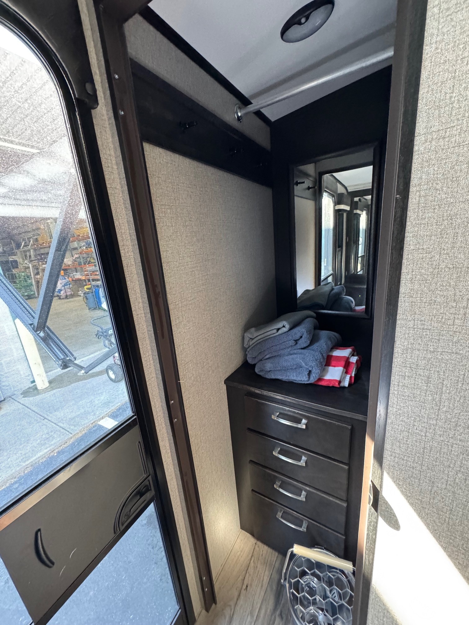 RV rental interior: main door with large window, and a closet area featuring a hanging rod, mirror, and dresser with towels.. Jayco White Hawk 2020