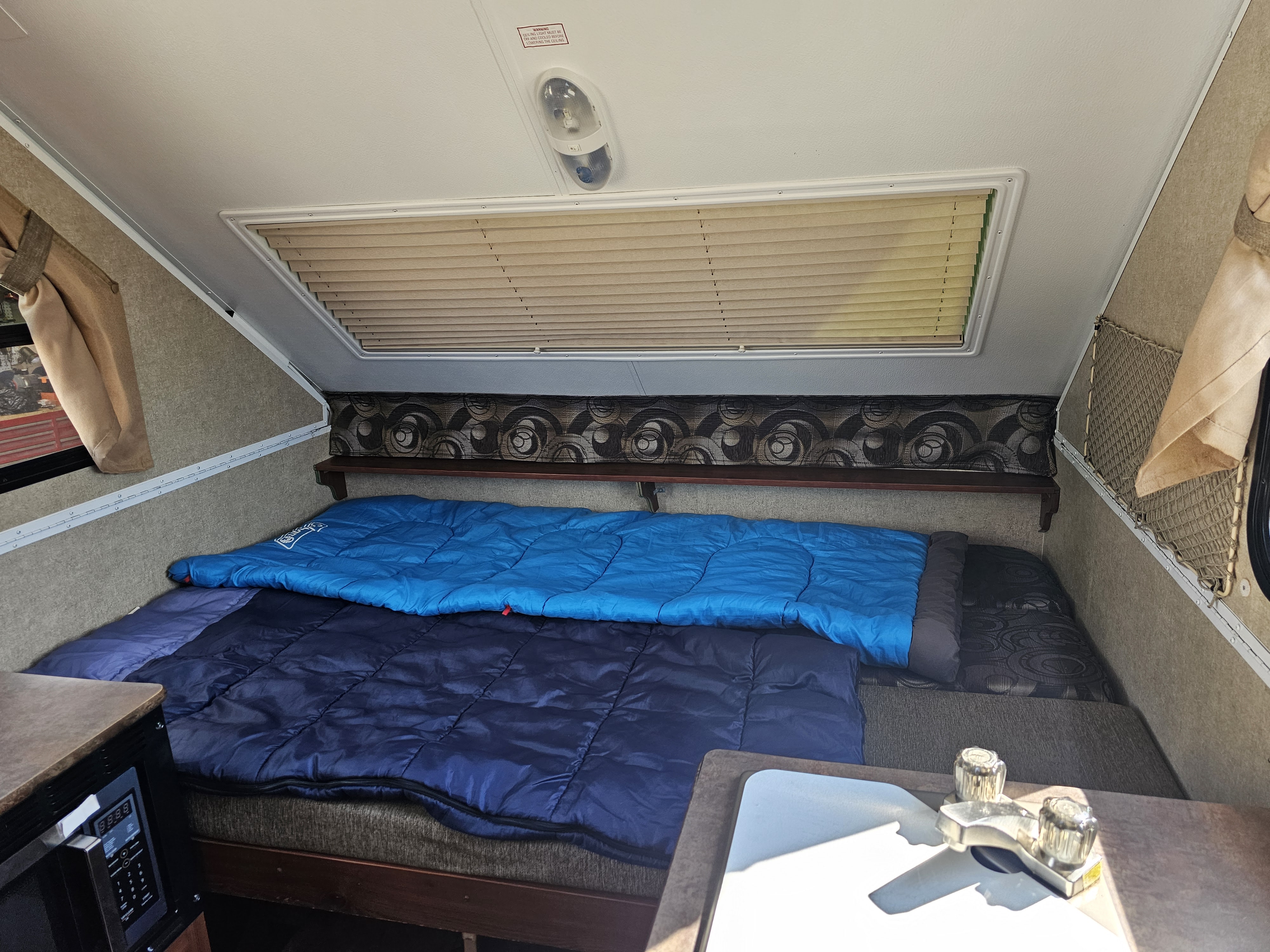 Experience our RV rental! Comfy sleeping area with sleeping bags, a compact kitchenette featuring a microwave & sink inside this camper.. Forest River Rockwood Premier 2014