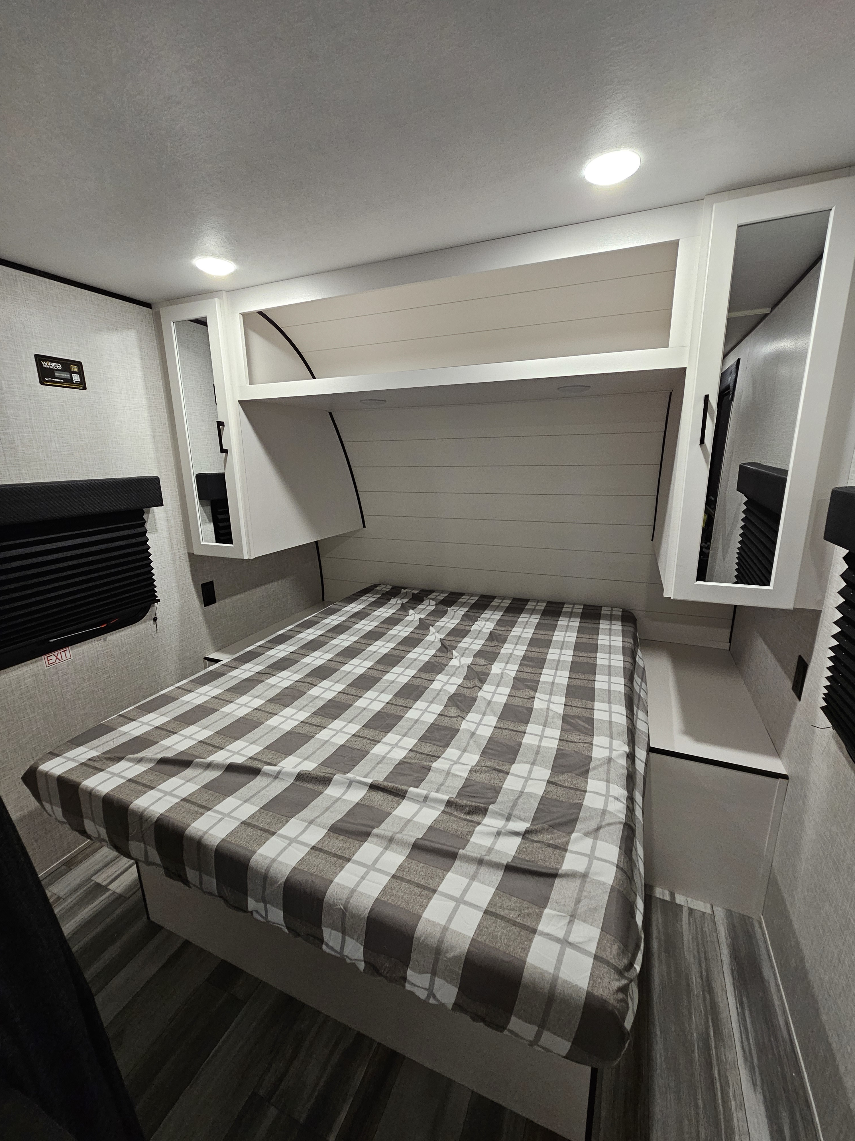 An rv rental bedroom with a brown and white plaid bed, white overhead cabinets, and built-in lighting.. jayco jayflight 260 bh 2025