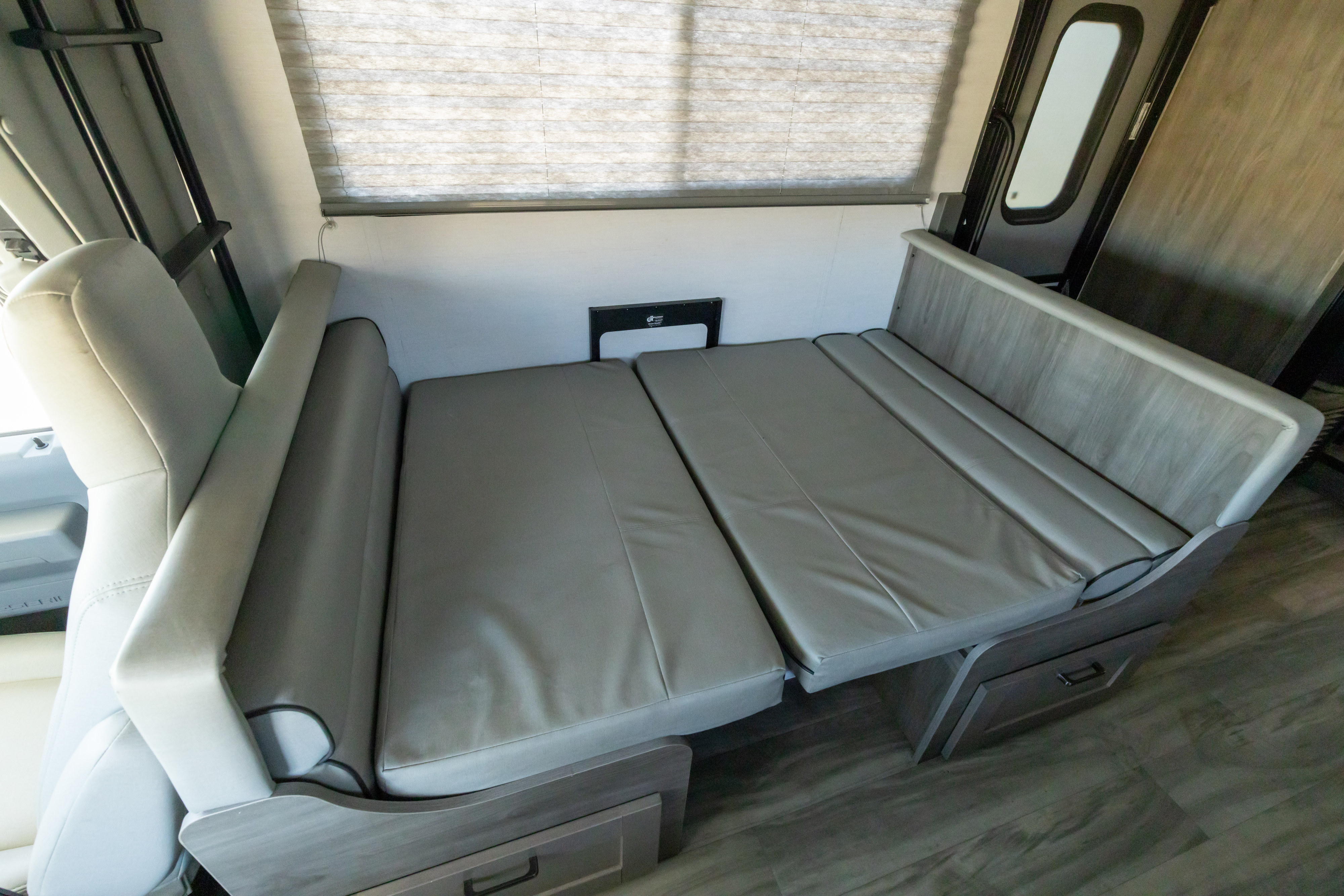 RV rental interior showing a grey upholstered dinette that converts into a comfortable bed for travel.. Gulf Stream Conquest 2024