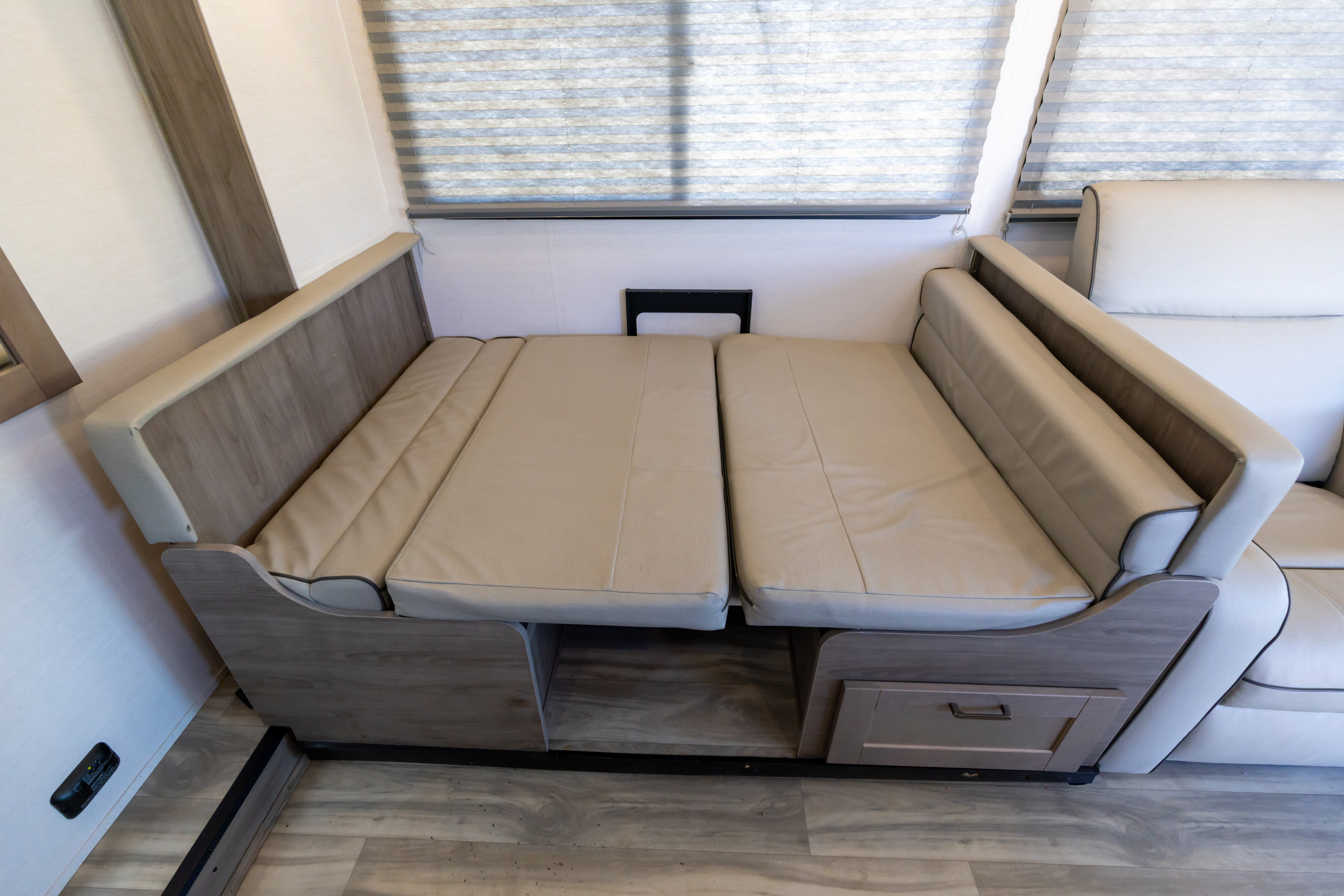 This RV rental features a versatile light-colored dinette sofa easily converted into a bed, with storage drawers visible.. Gulf Stream Conquest 2024