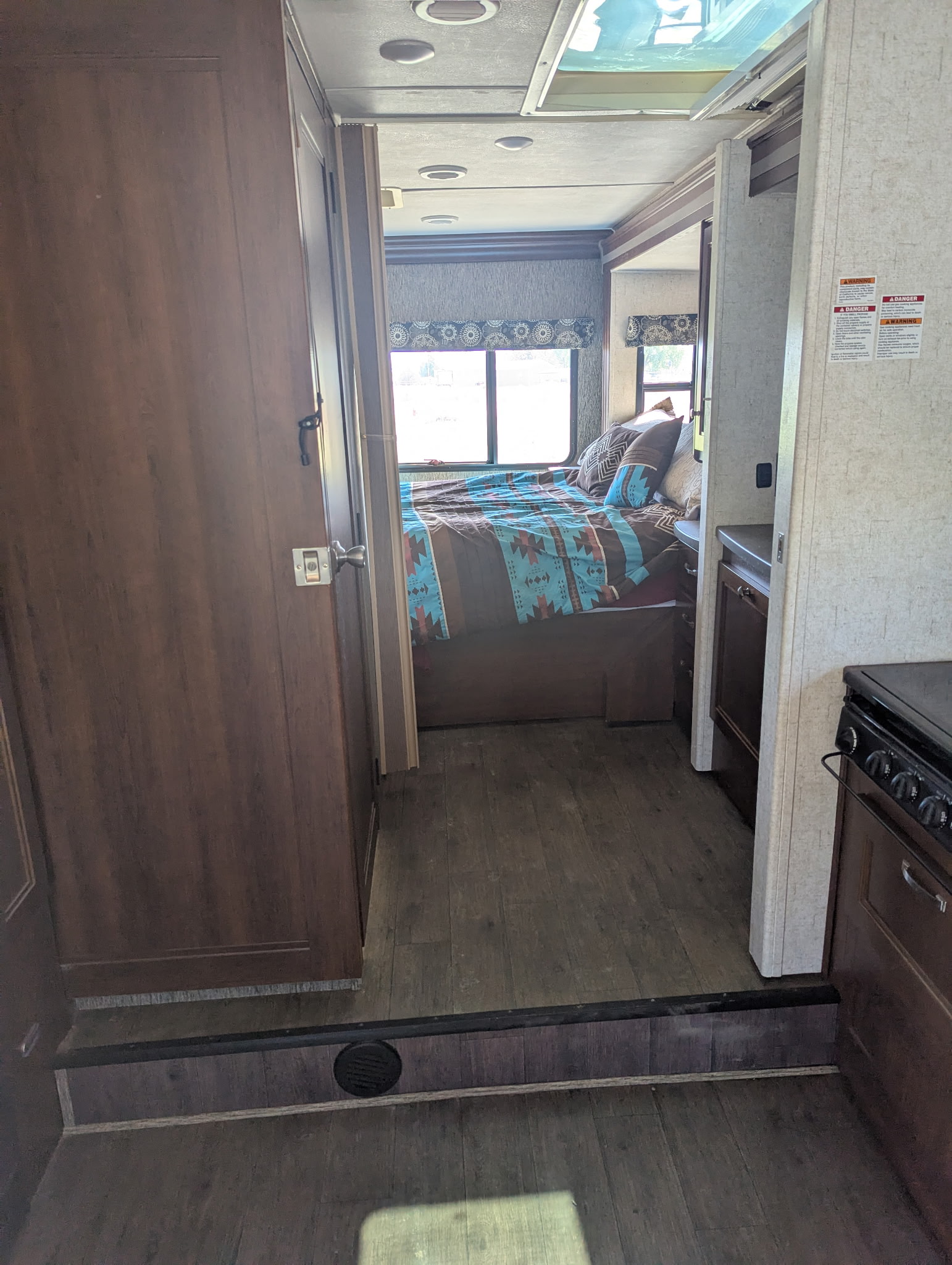 RV rental interior: a comfy bedroom with Southwestern-patterned bedding, and a glimpse of the kitchen through the doorway.. Forest River Sunseeker 2017