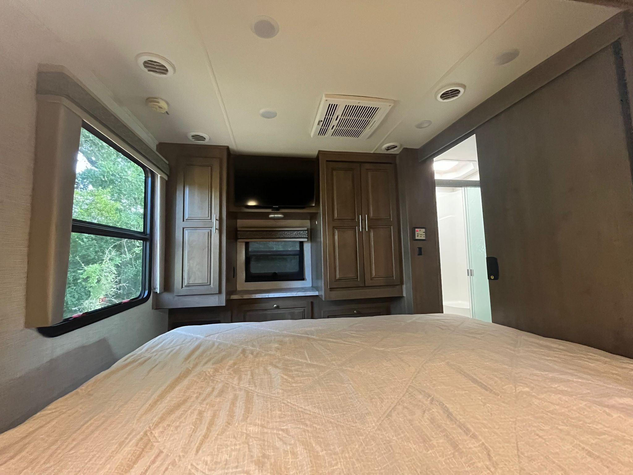 Cozy RV rental bedroom featuring a comfortable bed, entertainment center, cabinets, and direct bathroom access.. Georgetown GT5 2019