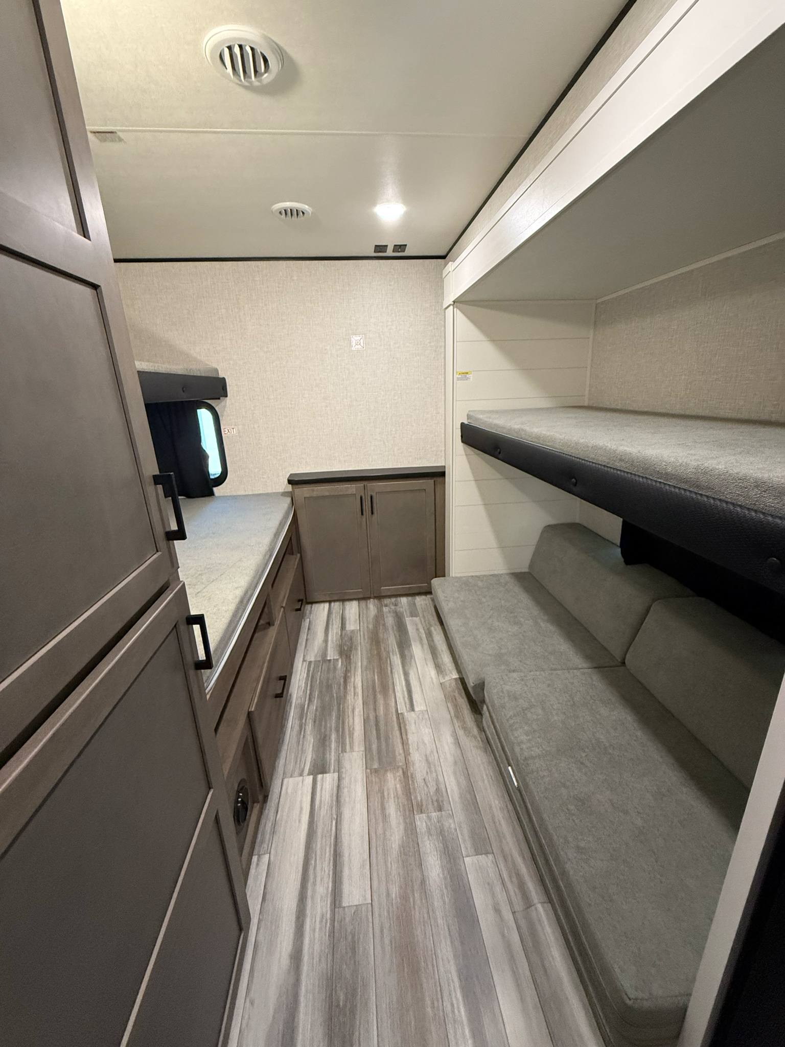 RV rental interior: A cozy bunkhouse with bunk beds, a gray sofa, wood-grain flooring, and storage cabinets.. Jayco Jay Flight SLX 2024