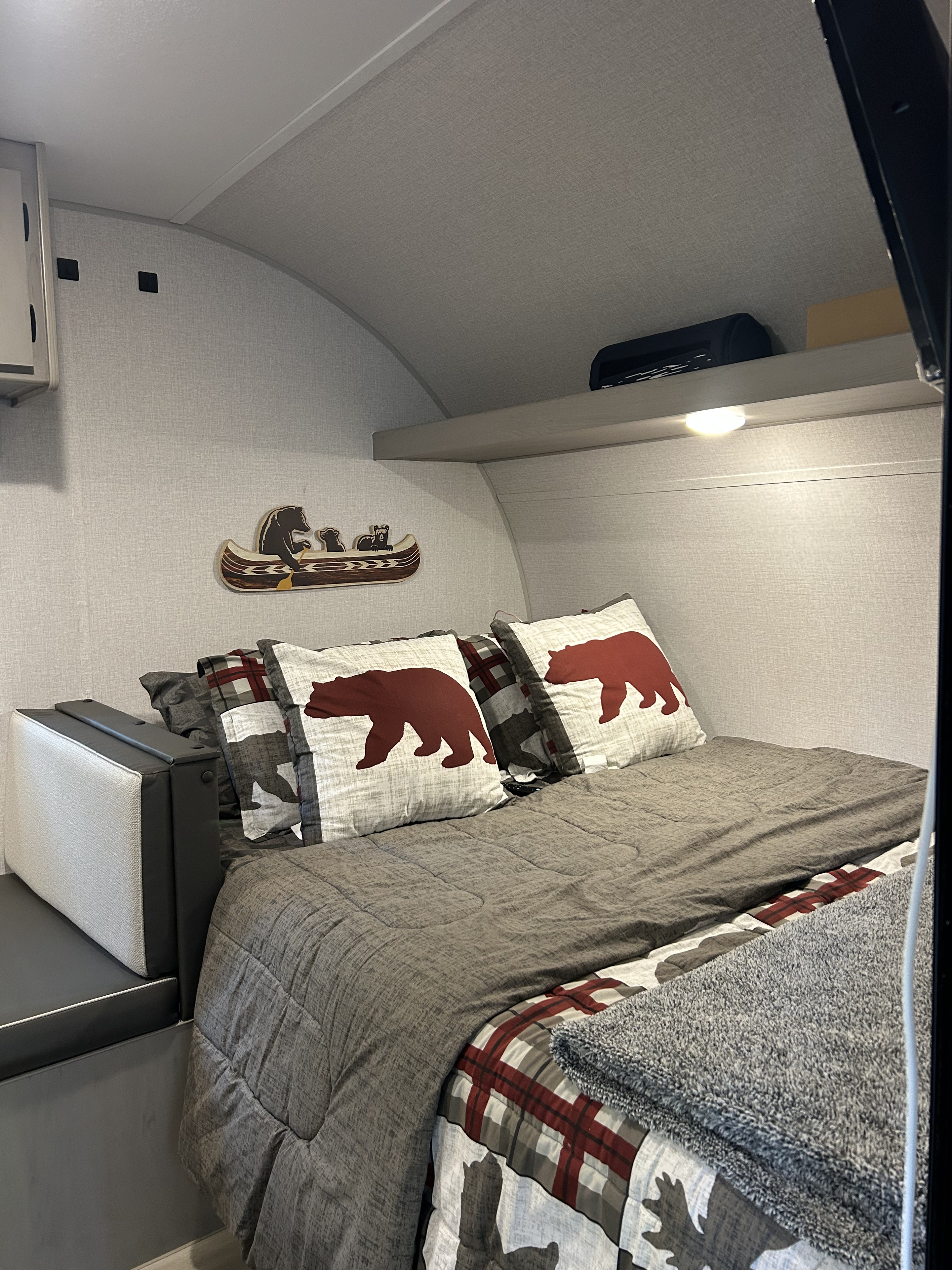 Relaxing RV rental bedroom: bed with bear-themed pillows, plaid accents, and rustic canoe decor.. Clipper 17CBHCADET 2024