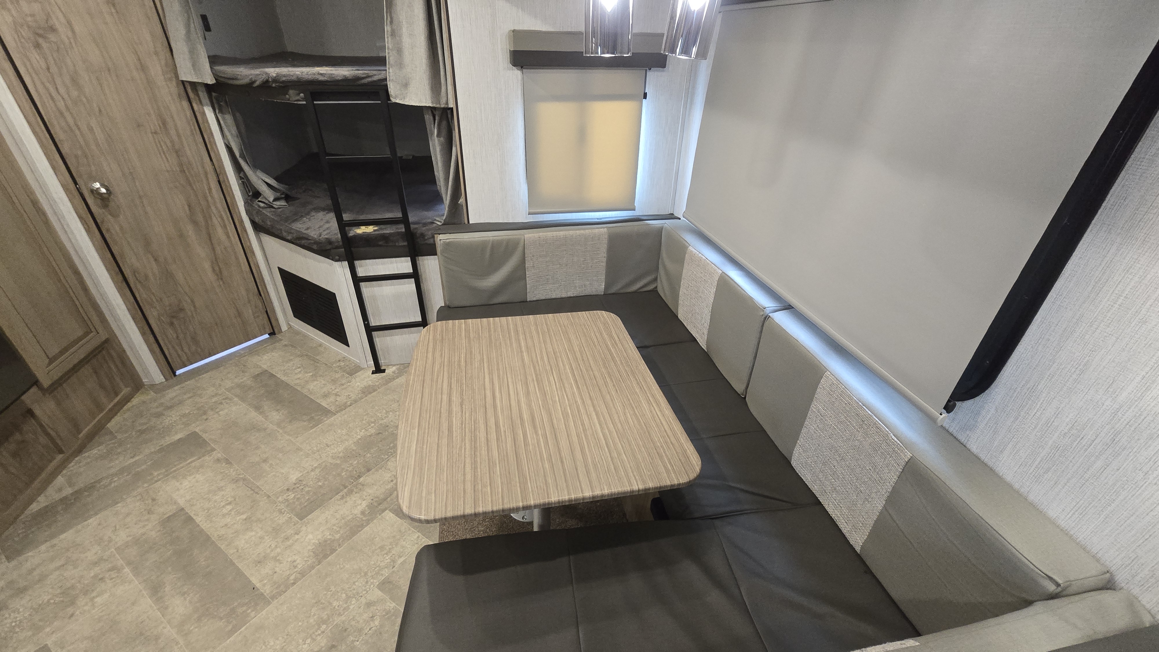 Inside an RV rental: a U-shaped dinette, bunk beds with ladder, window, and light wood-look floor. Compact travel comfort.. Palomino Solaire 2022