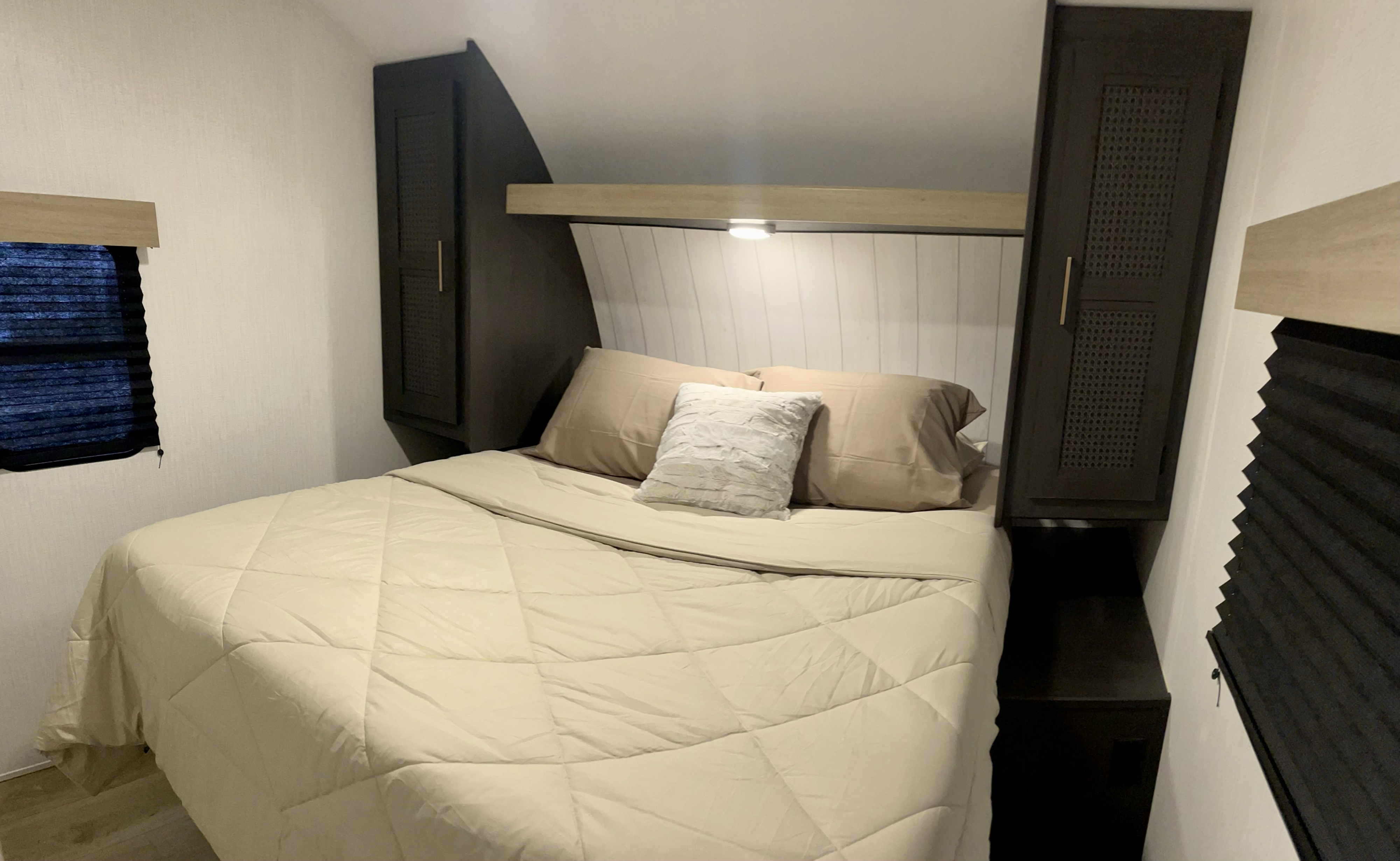 Inside an RV rental: a bright bedroom with a queen bed, twin wardrobes, reading lights, and pleated blinds for privacy.. Heartland RVs Pioneer Trail Blazer 2024