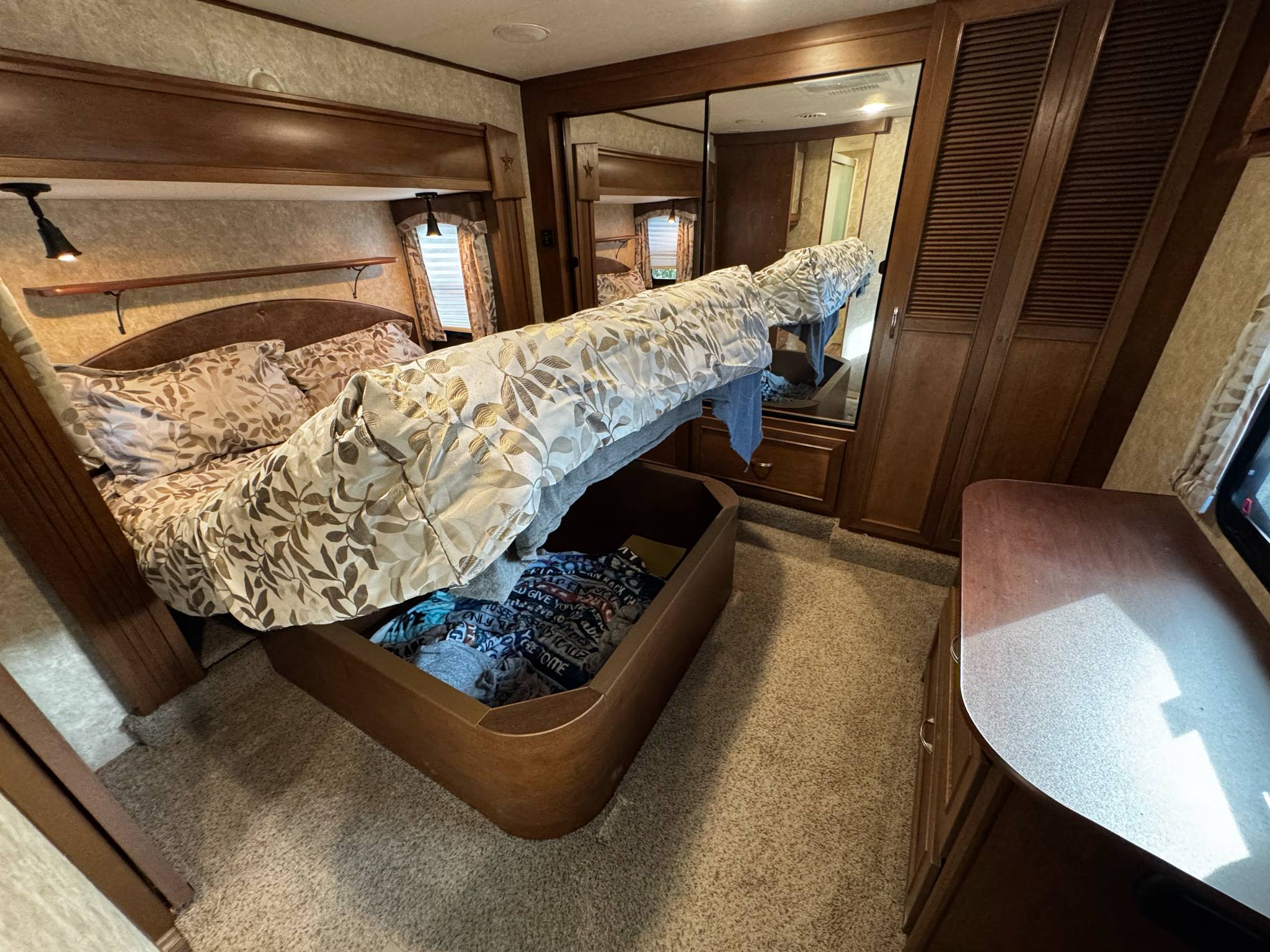 RV rental bedroom showcasing lift-up bed for convenient under-bed storage filled with clothes.. Highland Ridge RV Mesa Ridge 2017