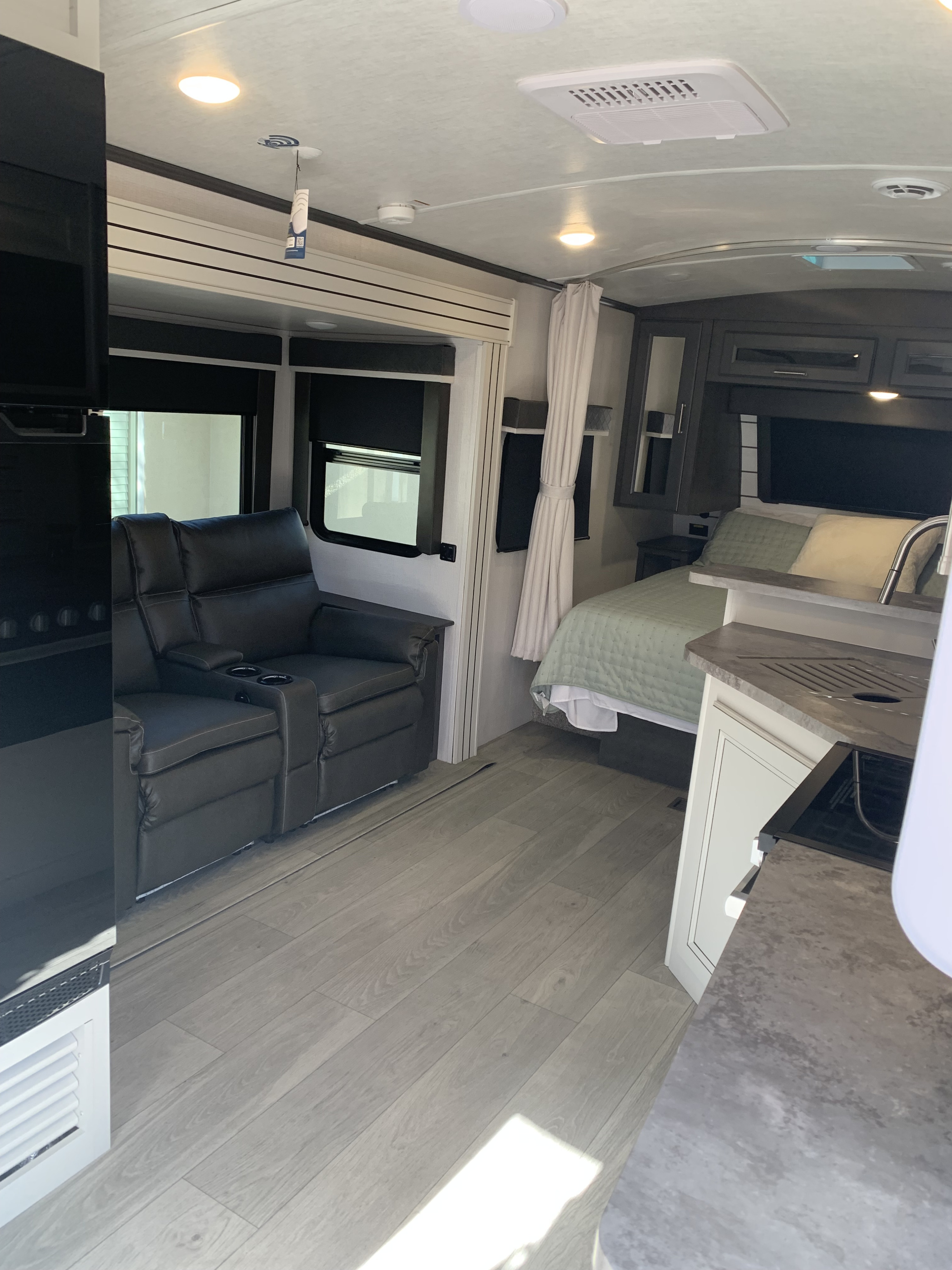 Spacious and modern RV rental interior featuring a cozy living area with recliners, a comfortable bedroom, and functional kitchen space.. Keystone RV Cougar 2024