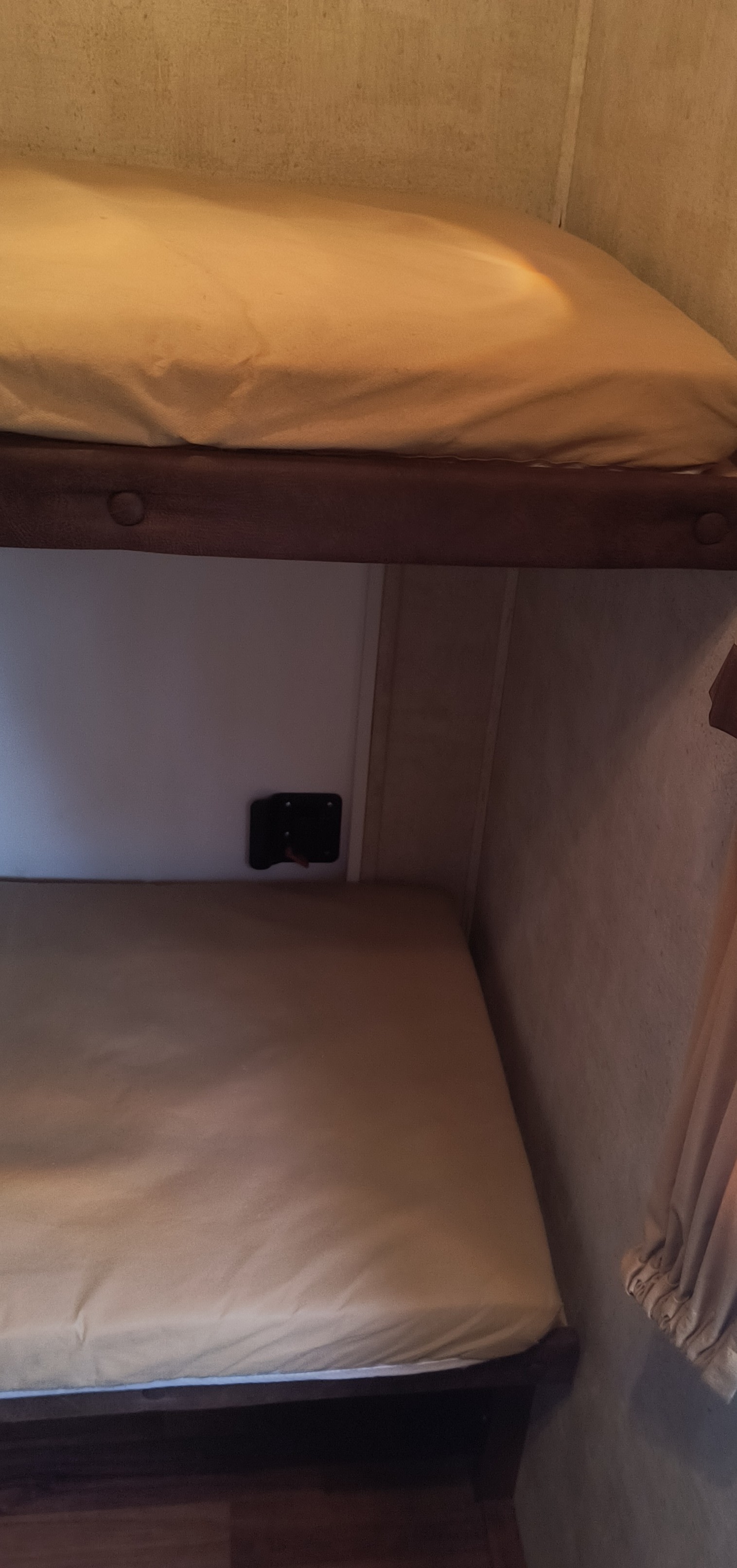 Cozy bunk beds in an RV rental, featuring light-colored mattresses. A wall-mounted fixture is between the bunks.. Keystone RV Sydney 10th Anniversary 2012