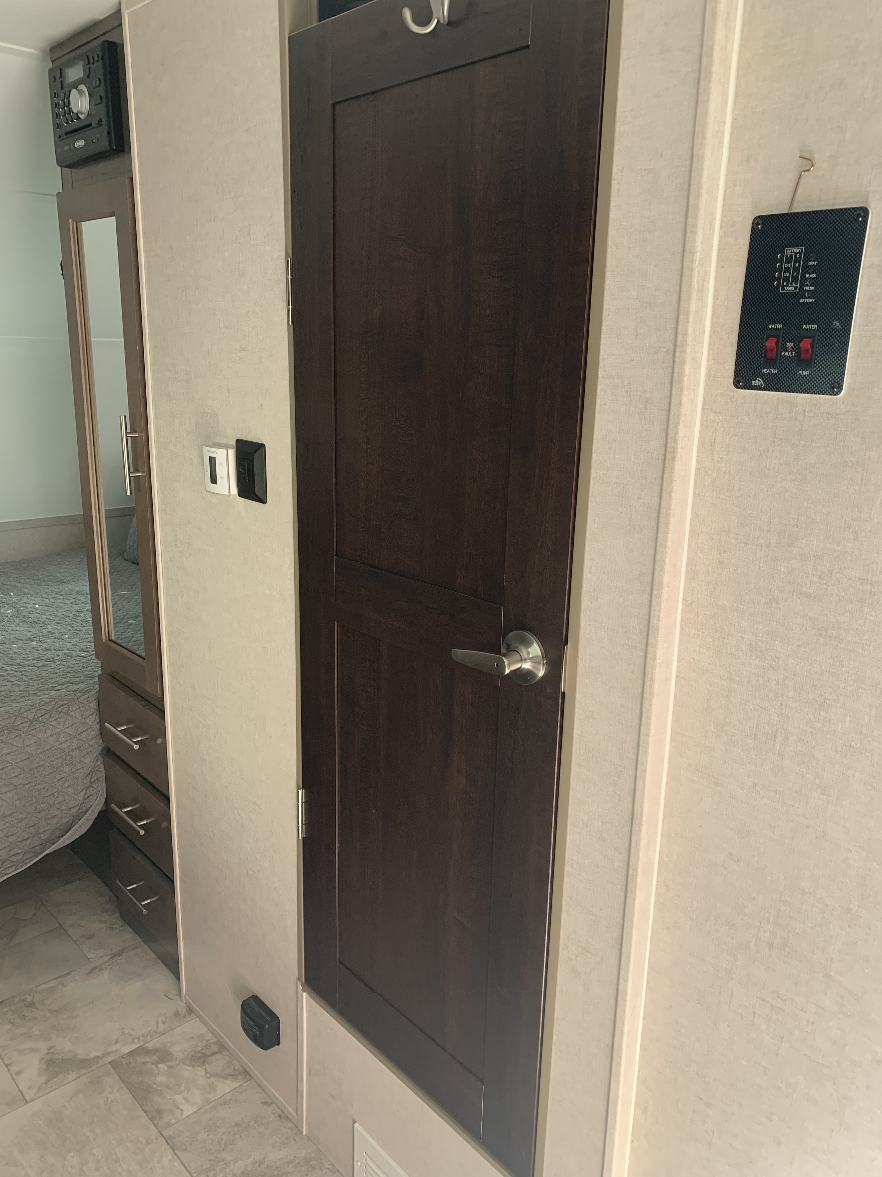 This RV rental interior features a dark wood door, mirrored closet, stereo, and tank/water control panel.. R-Pod Hood River Edition 2017