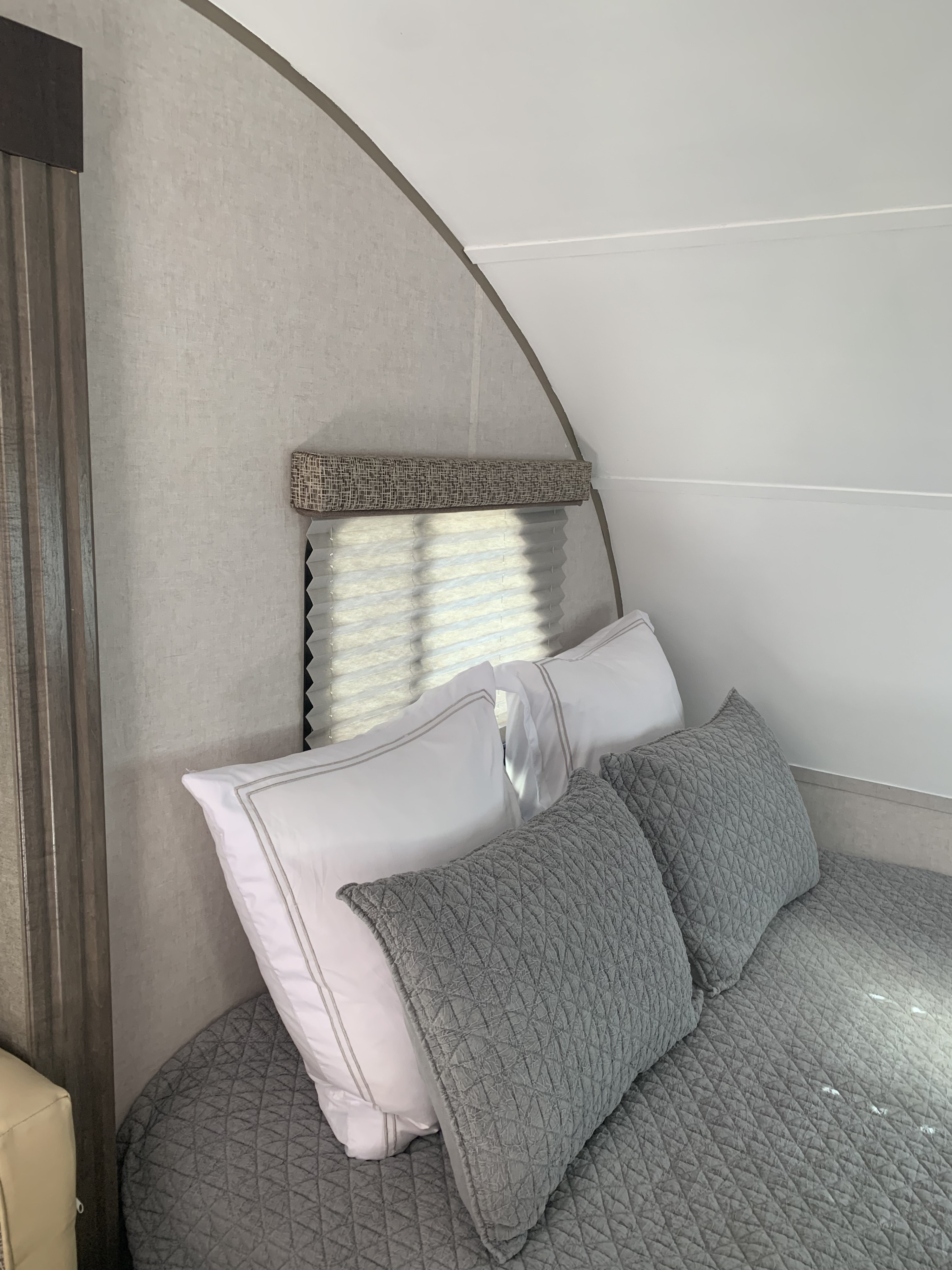 RV rental interior: A cozy bedroom with a bed, white & gray pillows, and a window with blinds.. R-Pod Hood River Edition 2017