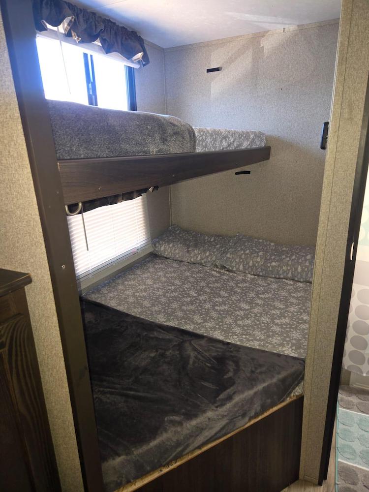 RV rental bunk beds: two cozy sleeping areas with gray bedding & window. Ideal compact accommodation for travel.. Keystone RV Springdale 2018