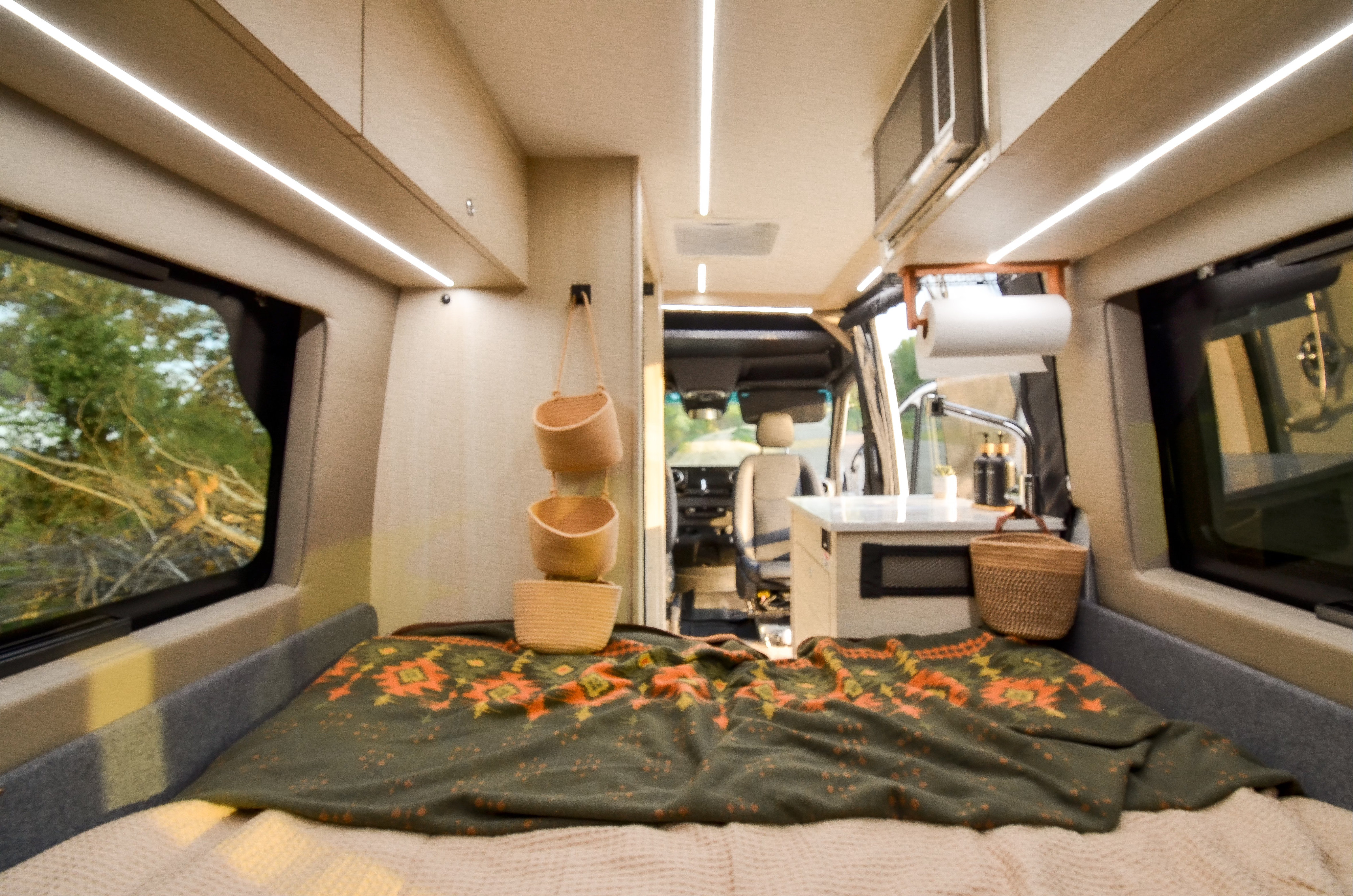 Inside an RV rental: a comfortable bed, functional kitchen, and scenic outdoor views through large windows.. Cahaba Cahaba Class B 2021