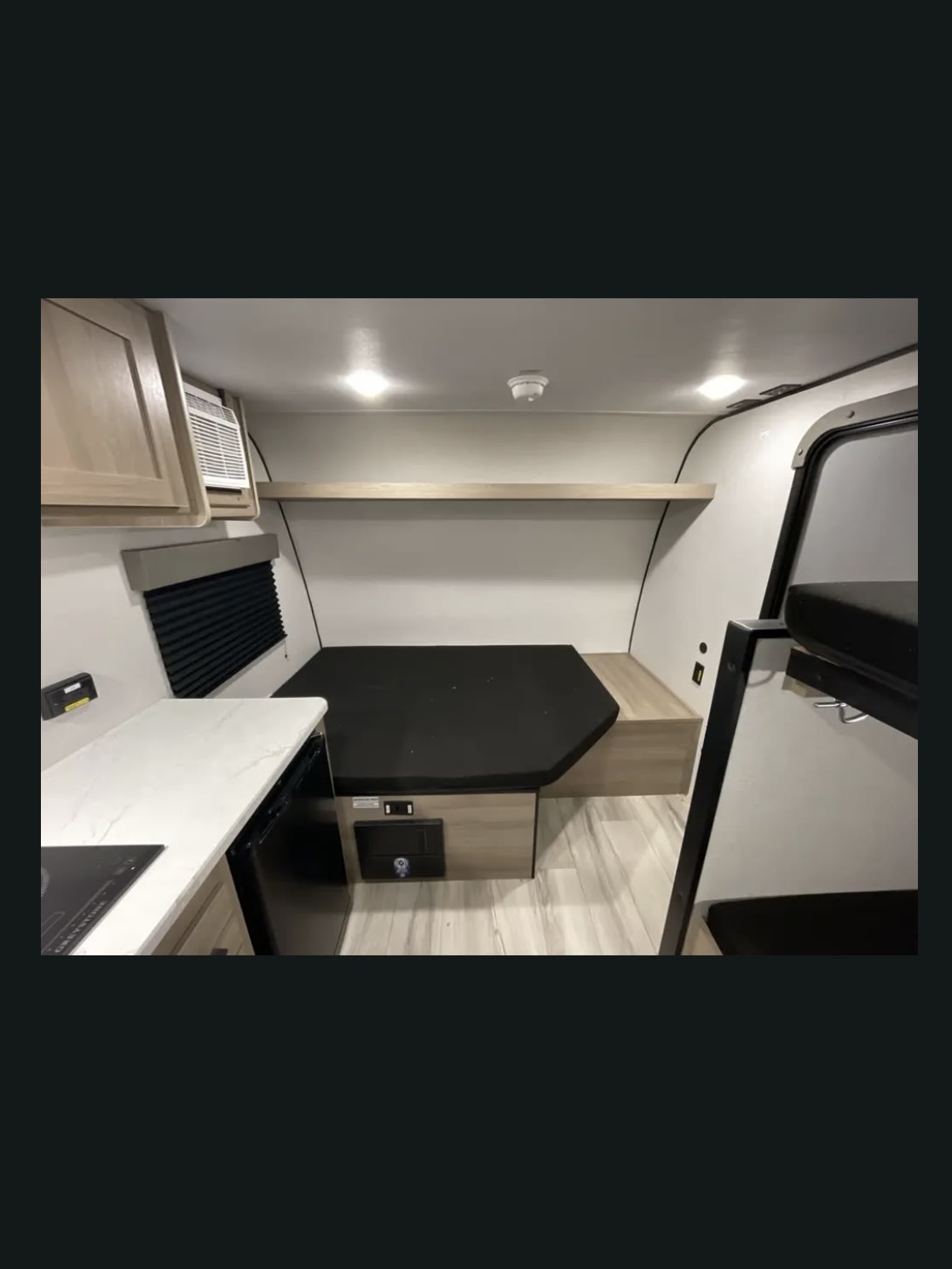 Bright RV rental interior with a bed, kitchenette, bunk beds, and light wood accents.. Coleman 13b 2025