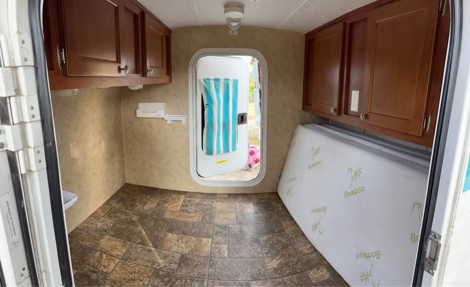 RV rental interior features: wood cabinets on both sides, tile-patterned floor, and a Bamboo mattress ready for use.. Riverside RV White Water 2014