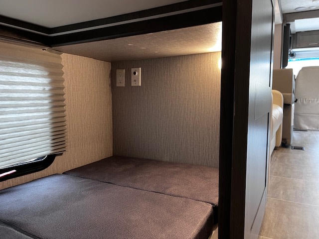 RV rental interior: A cozy bunk with mattress, window, and outlets. Perfect compact sleeping space.. Forest River Coachmen Mirada 2022