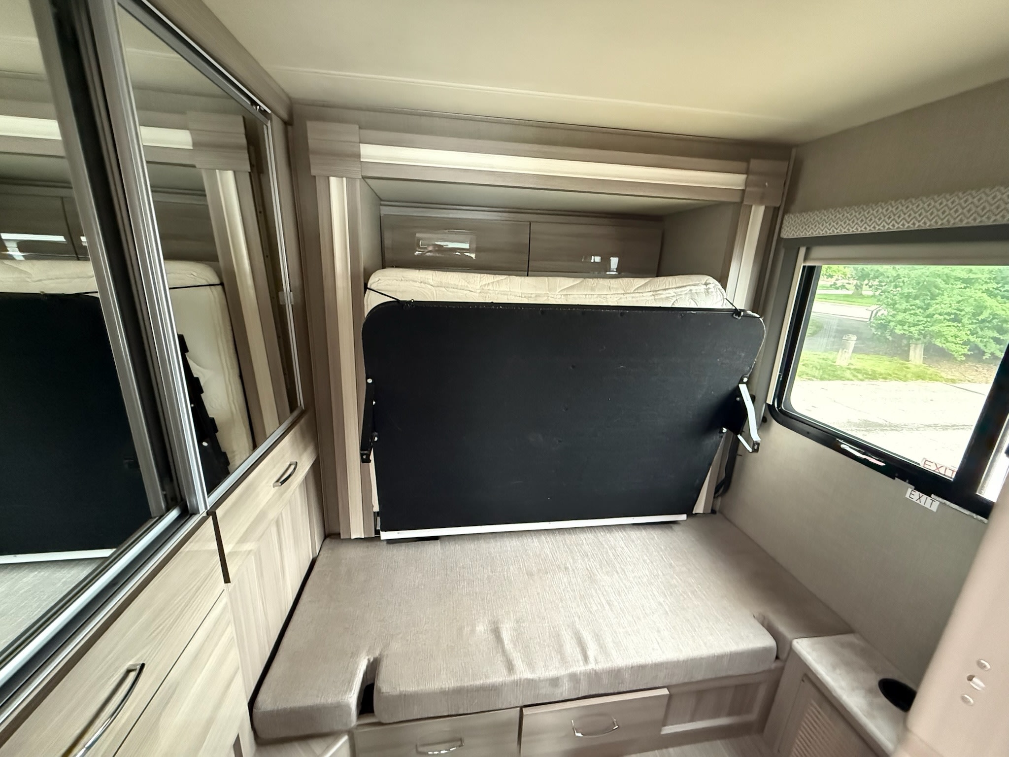 Explore this RV rental's versatile interior featuring a folded murphy bed above a dinette. Mirrored closet and storage optimized for compact living.. Thor Tiburon 2021