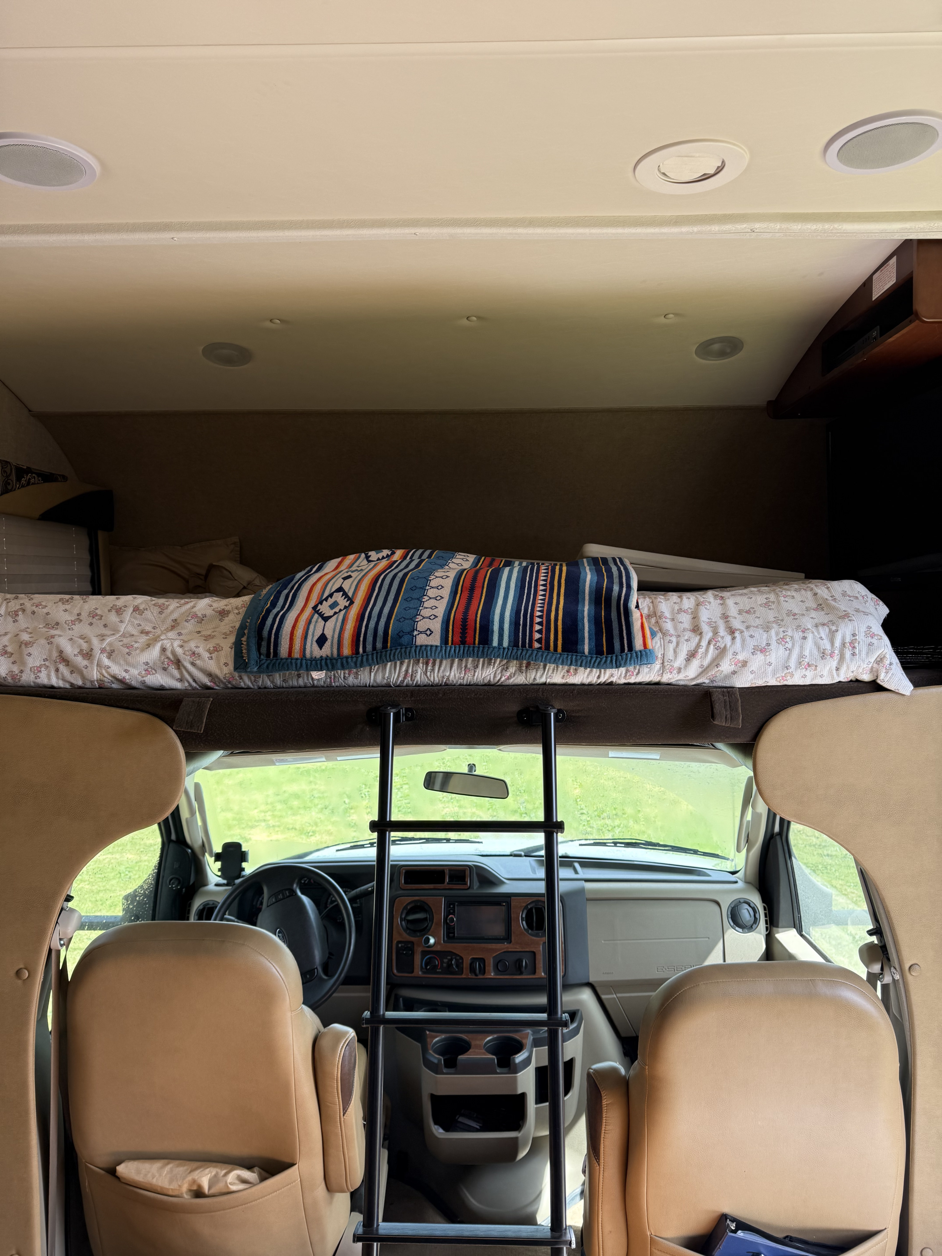 RV rental interior: A cozy over-cab bunk bed with a ladder leading to the front cabin and windshield view.. Jayco Greyhawk 2015