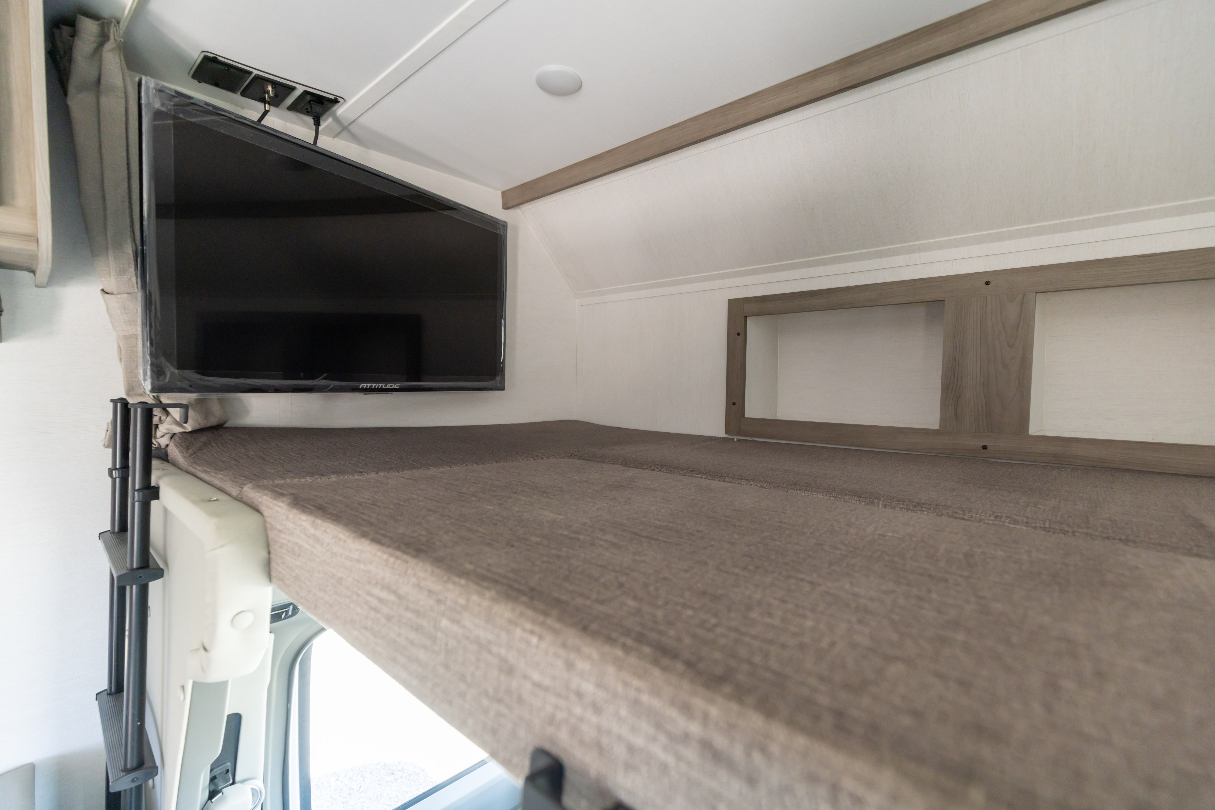 RV rental interior: Upper bunk area features a comfortable mattress, wall-mounted TV, and handy storage cubbies.. Gulf Stream Conquest 2024