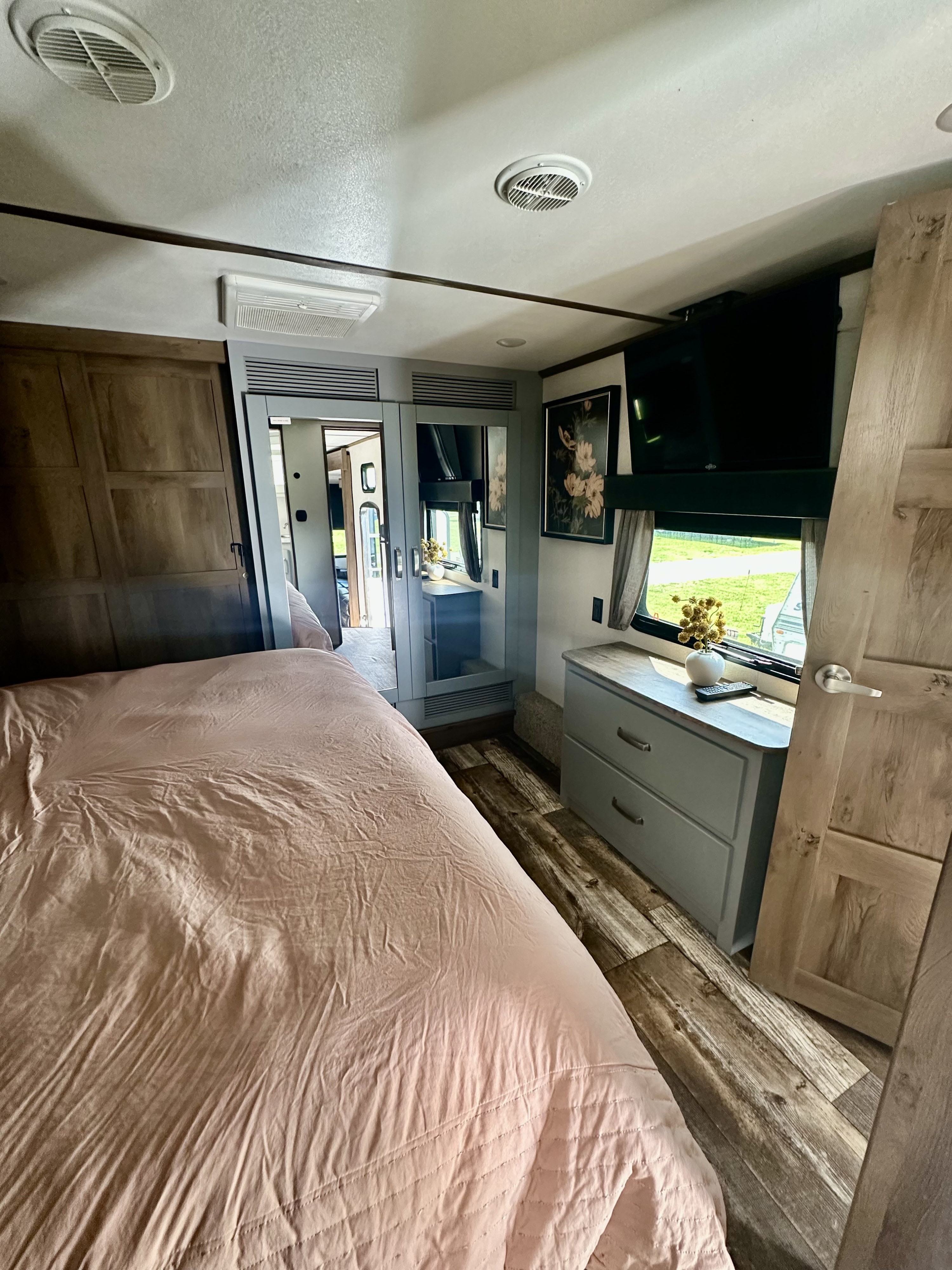 Spacious and comfortable RV bedroom interior. Perfect for your next RV rental adventure, featuring a large bed, dresser, and TV.. Keystone RV Fuzion Toy Hauler 2021
