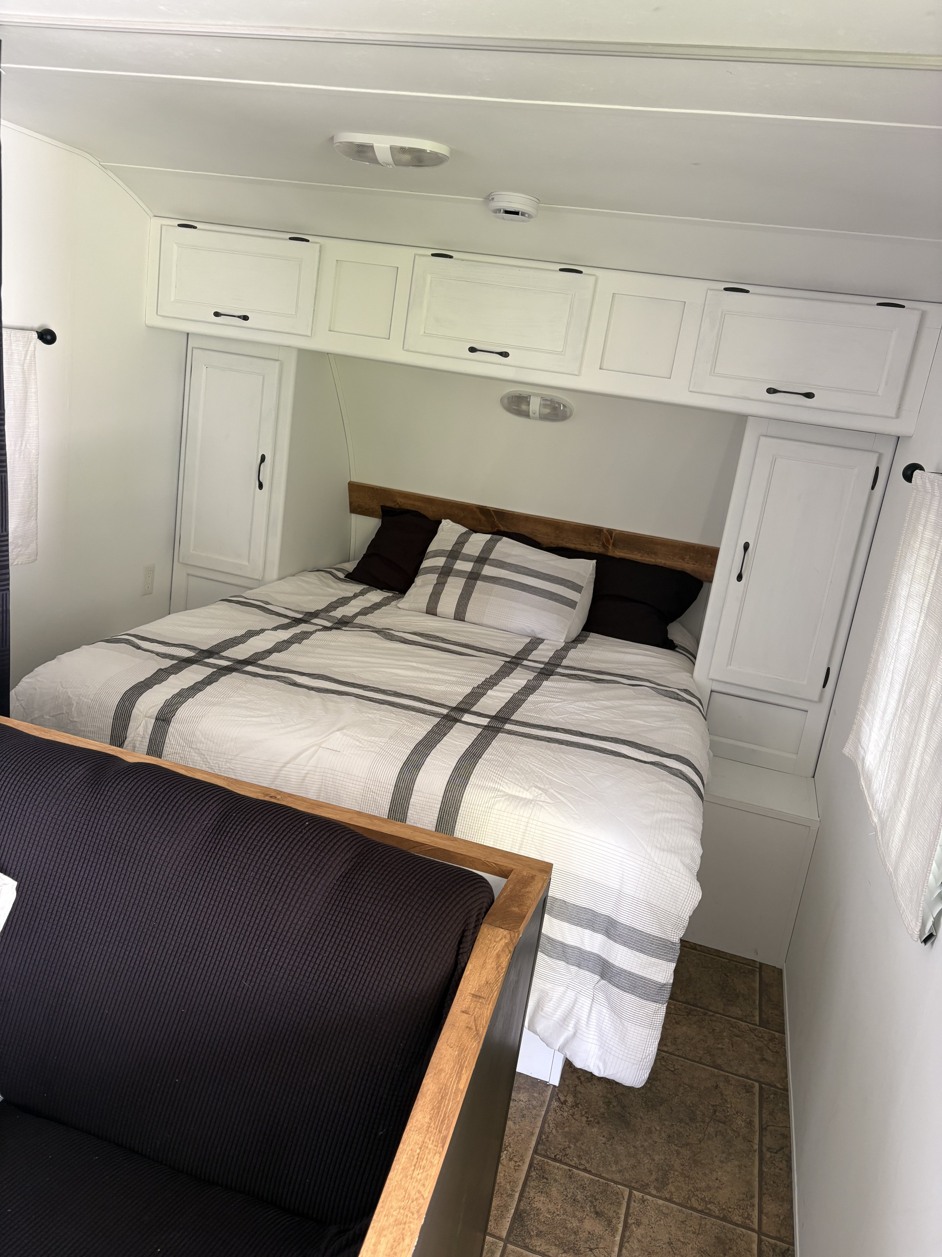 Cozy RV rental bedroom with striped bedding, sleek white cabinetry, and warm wood details.. Forest River Cherokee Grey Wolf 2012