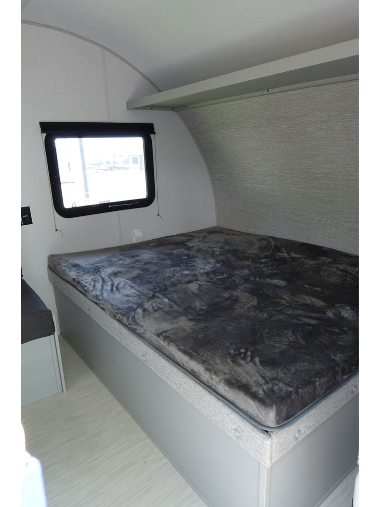 An rv rental's interior bedroom with a comfy bed, dark blanket, window, and overhead storage shelf.. Forest River Salem FSX 174BHLE 2024