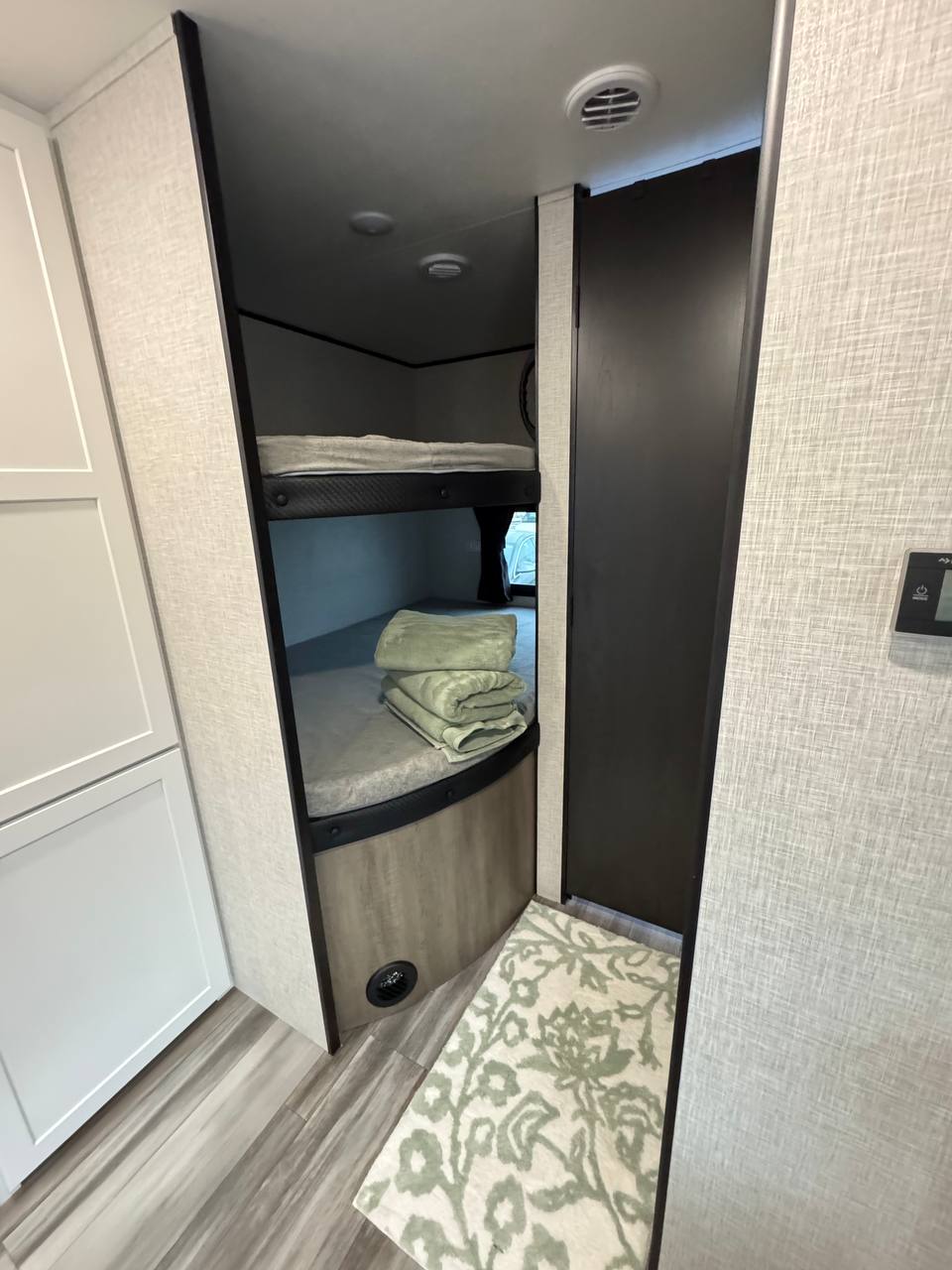 Compact RV rental interior with bunk beds, neatly folded towels, and a cozy rug. Ideal for family travel.. Jayco JAY Flight SLX 261BHS 2025