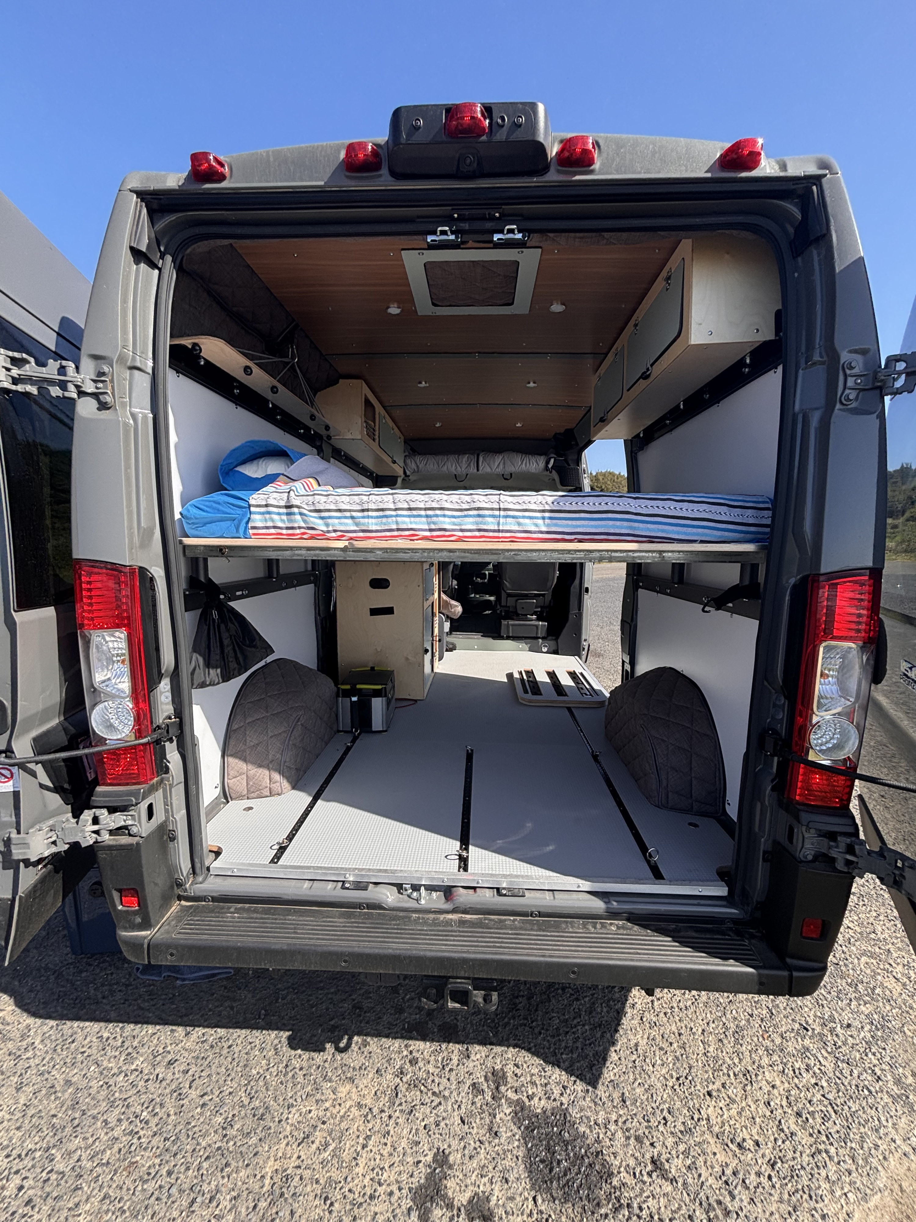 Step inside this organized camper van RV rental! Featuring a raised bed, storage, and track flooring from the open rear doors.. RAM RAM PROMASTER 1500 2024