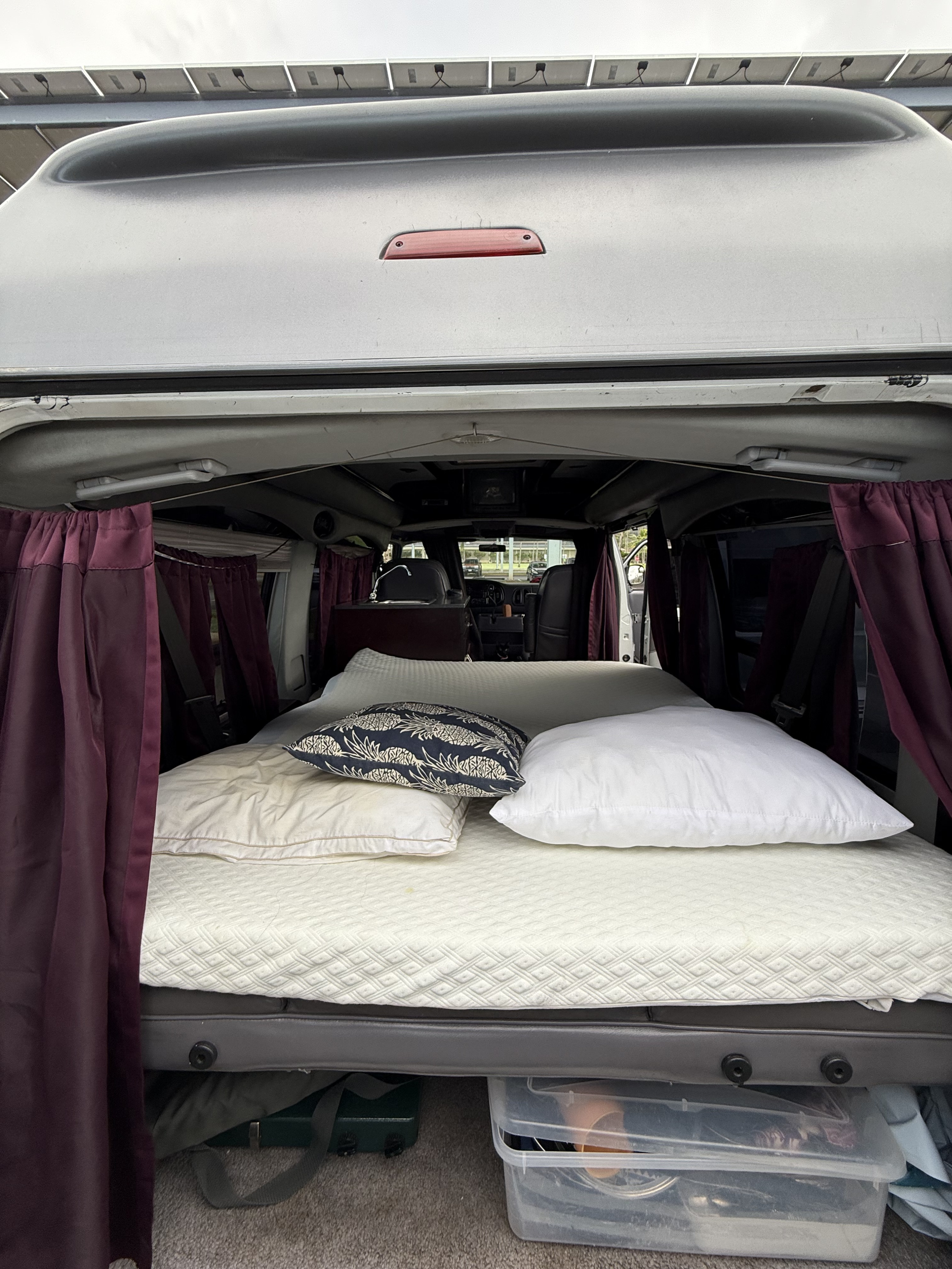 RV rental ready: comfortable camper van interior with a bed, pillows, storage, and rooftop solar panels. Adventure awaits!. Dodge Ram 1500 2000