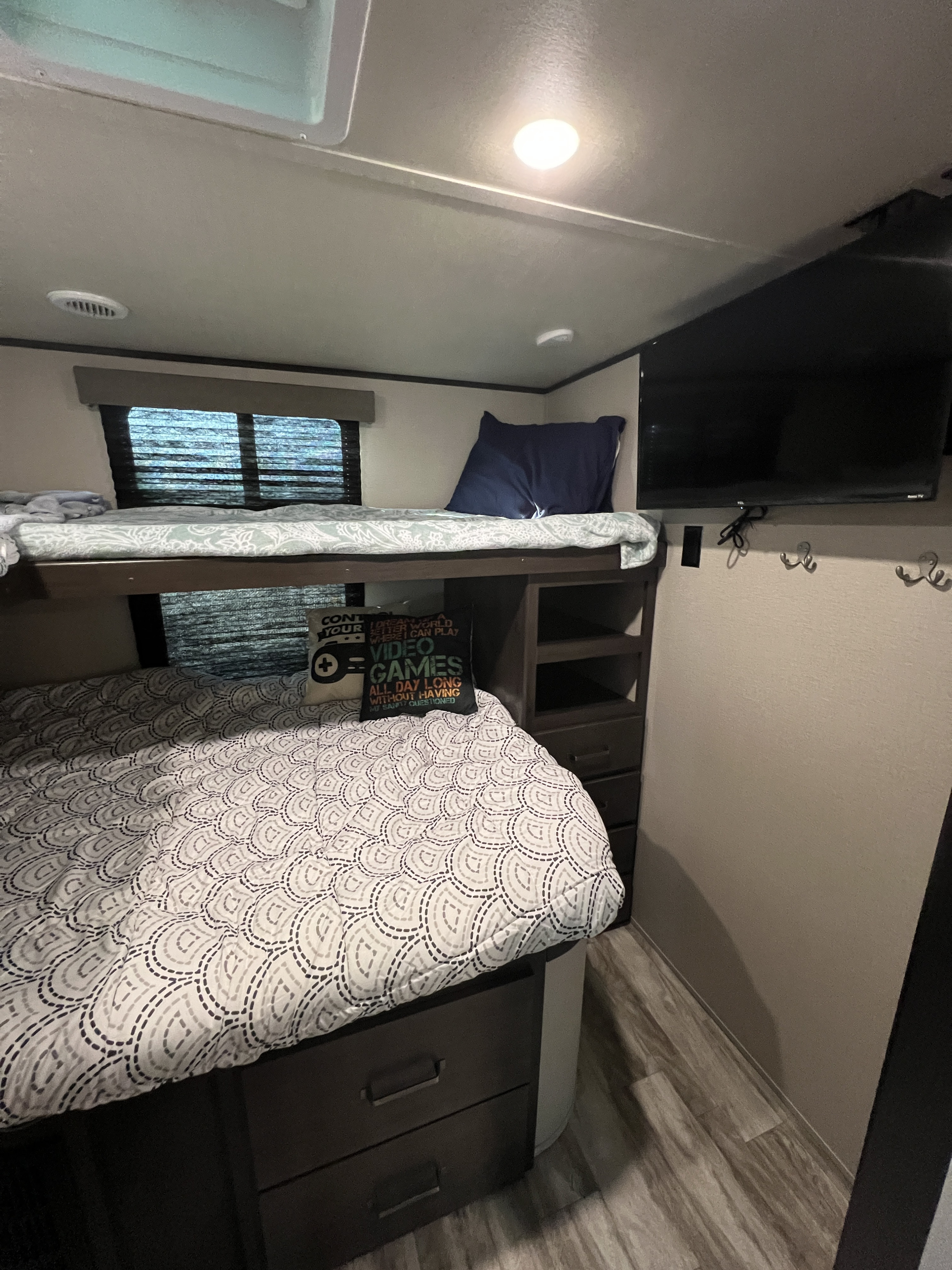 Inside an RV rental: comfortable bunk beds, mounted TV, and built-in storage make for a practical and fun travel space.. Grand Design Transcend Xplor 2021
