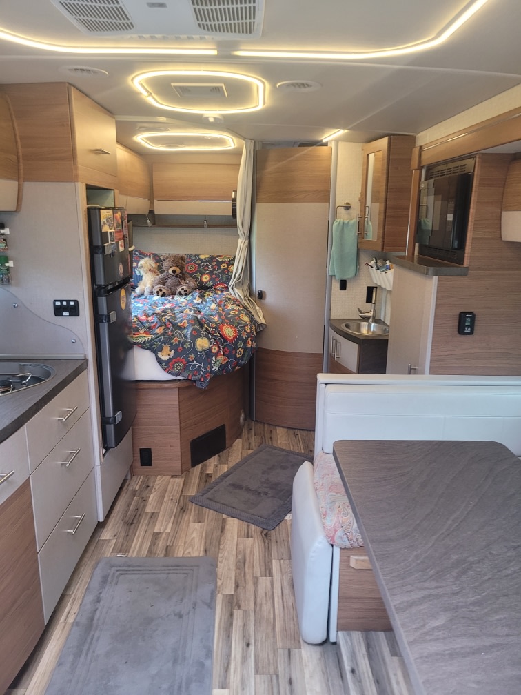 Cozy interior of a modern RV rental, featuring a bed, kitchen, and dinette area for comfortable travels.. Winnebago Navion 2017