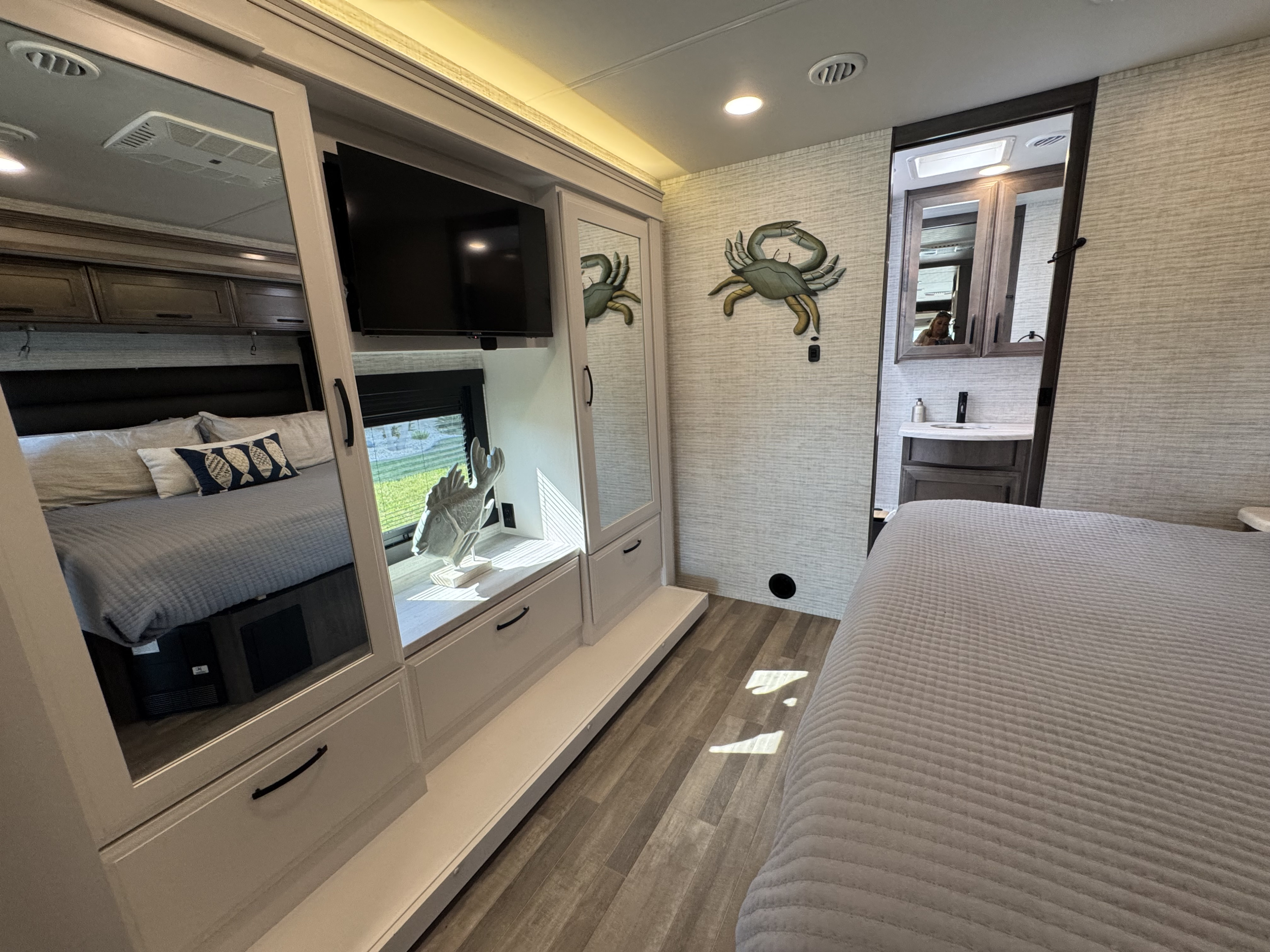 Modern RV rental bedroom with mirrored wardrobe, TV, bed, and ensuite bathroom with vanity.. Entegra Vision XL 36C 2025