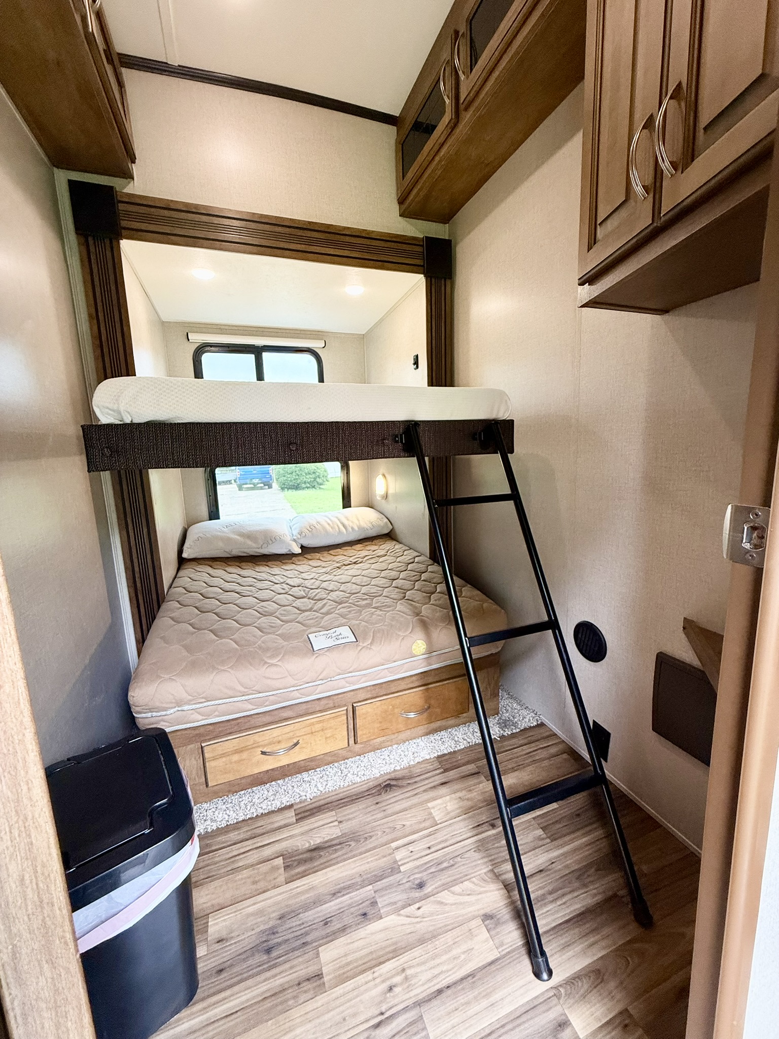This RV rental features a cozy camper interior with bunk beds, a ladder for the top bunk, storage drawers, and a window view.. Coachmen Chaparral 2018