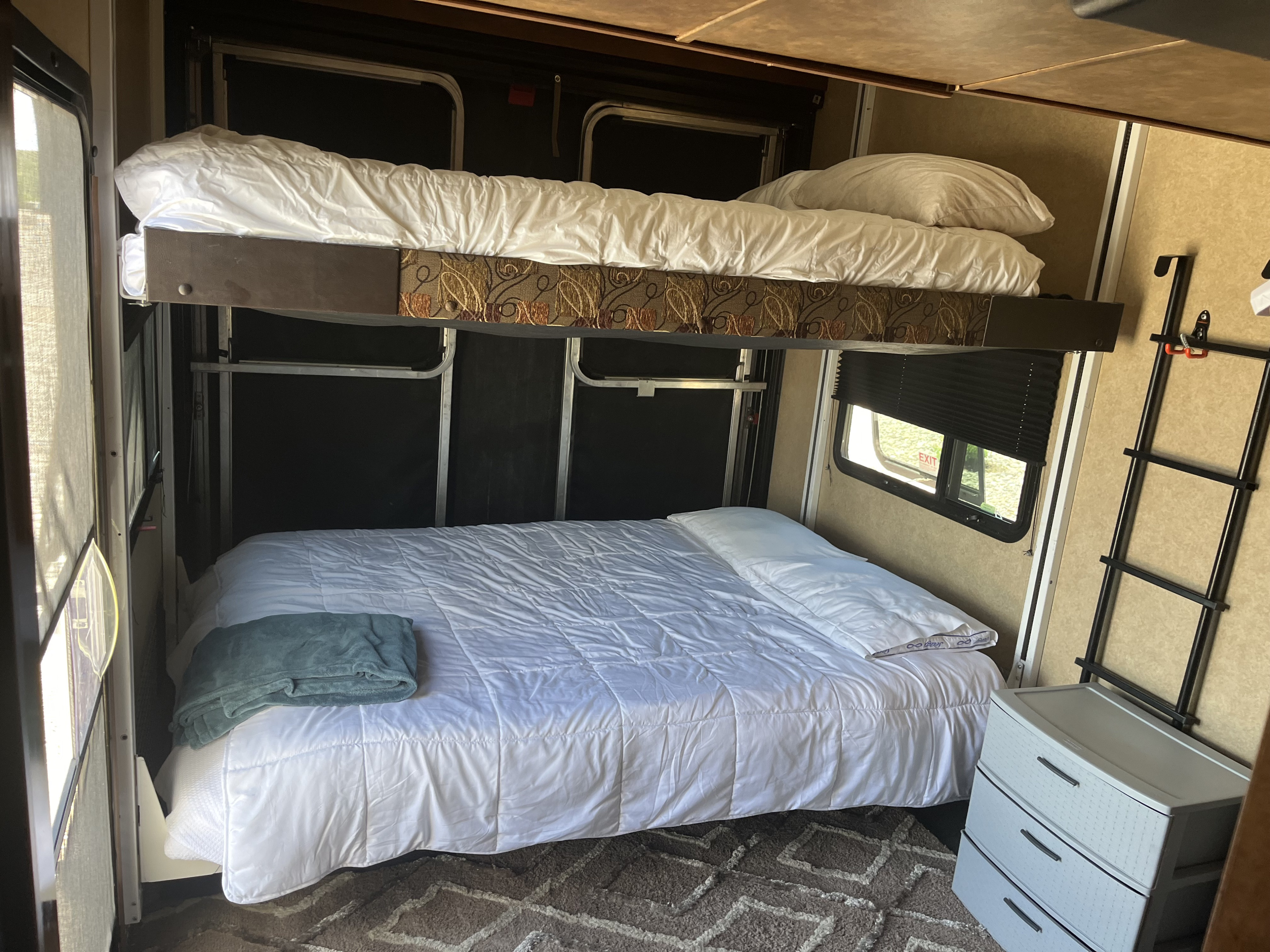 Inside an RV rental, showing the sleeping area with comfy bunk beds, white bedding, and storage. Ready for your trip!. Forest River XLR Thunderbolt Toy Hauler 2014