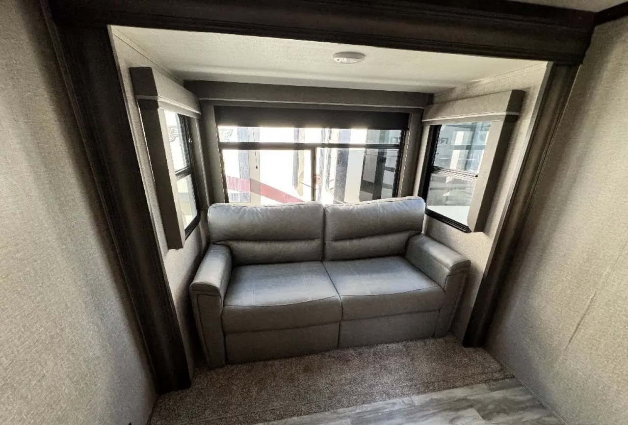 This RV rental offers a comfortable gray sofa in a dedicated slide-out living space with large windows.. Grand Design Reflection 2022